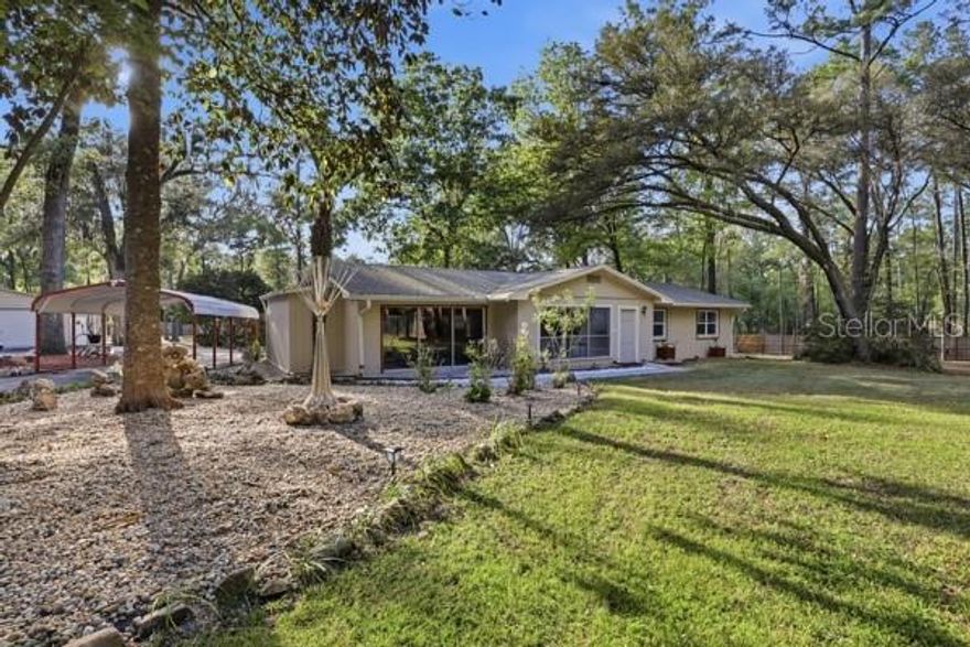 A Quiet Secluded Paradise! This wonderful home resides on 2.5 acres on the outskirts of Gainesville off NW 39th Ave with NO HOA to hassle you. Upon entering the gated drive, you will be welcomed with a well manicured yard with mature oak trees spread over the acreage. The home was well loved and taken care of with lots of thoughtful detail work throughout. When entering the home you will find a foyer that opens to a large open living area currently used as a dinning space. The spacious kitchen is well adorn with granite counters and complimenting stainless appliances including a double oven range. Lots of cabinets and counter space for the chef of the house. The family room has large windows that look out the front of the home and custom tile floor details, a wonderful room for entertaining. Off of the family room, you will find a large storage room as well as interior laundry room. The back of the home has a large glassed Florida room which overlooks the multi-level deck and gorgeous backyard.  Down the hallway you will find two guest rooms with warm tone luxury vinyl plank flooring and a guest bathroom. The primary bedroom is at the end of the hall with ensuite bathroom that has a walk-in shower and newly tiled floors. From the primary bedroom you have private access to the back deck area for your morning cup of coffee or to enjoy the fresh morning air. Behind the main home you have a detached in-law studio suite/guest house with its own private kitchen, bathroom, laundry and deck. Additional to the property is a 900sq ft detached garage shop for all of the big toys. The garage is insulated and has a window unit and split unit AC conditioning the garage and workshop room in the back. The workshop is complete with 110v and 220v electrical access. The whole yard is fenced in and offers plenty of space for your pets to run. The underbrush has all been cleared from under the oak trees and offers a park-like setting for relaxing. The main HVAC is 1 year old and water heater is 5yrs old. HVAC in Guest house is about 3yrs old.  Four stage water filtration system is included on the well system. New gutters with gutter guards have been installed for easy maintenance. Fresh interior paint throughout the home. Smart lights, home sound system, in-floor safe and hardwired security system all in the main home. The landscaping and lighting around the home really make this property a show piece for entertaining. The neighborhood has private access at the back to Jonesville park with nice walking paths. Property is zoned RE-1 and may be able to be divided for a second residence. Come take a tour of this wonderful property before it's gone!