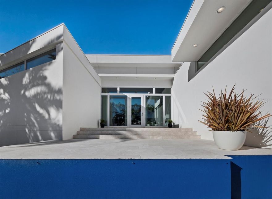 An icon of modern design in the style of the world-renowned Sarasota School of Architecture, 1235 Center Place combines award-winning pedigree with exceptional luxury in a setting that is as coveted for its natural beauty and access to amenities as for its storied mid-century and modern estates. Known as the Light Box House for its distinctive angles and use of glass walls to showcase courtyard and exterior views, this home was custom built in 2012 by the current owners to foster both idyllic privacy and elevated hospitality. The home and architect Jonathan Parks have been widely celebrated for its design, winning the AIA Tampa Bay Merit Award for Architecture and the Grand Aurora Award for a custom home, with features in the Herald-Tribune’s Style Magazine, Sarasota Observer, and HomeDSGN magazine. Occupying the corner lot of Westway and Center and two doors away from the famed Umbrella House, the home is thoughtfully oriented around a central pool that serves as a focal point for both reflection and recreation. Stretching between north and south wings that gently delineate spaces for private retreat and open entertaining, 3,700 A/C square feet encompass three bedrooms with three and a half bathrooms, dual offices, an open concept gourmet kitchen and adjacent dining and living space, all purposefully positioned to capture optimal light and accentuate the interplay of built features with the tropical landscape. An elegant contrast to the brilliant sky and foliage outside, the interior is a refined gallery that meticulously balances walls of glass with solid surfaces for display and function, from art-hung walls to Caesarstone countertops. While complementing the mid-century style of surrounding homes, contemporary construction here offers the significant advantages of elevation for flood consideration, high-efficiency impact rated materials, and modern integrations including heated primary bathroom floor, motorized window coverings, Generac generator, LED landscape lighting, and more. Recent upgrades include two Carrier Infinity HVAC systems installed in 2025 and 2024. Lido Shores is coveted for its concentration of mid-century, modern, and post-modern homes, with masterpieces by Paul Rudolph, Carl Abbott, Don Chapell, and others renowned for their architectural influence. Serene and private but within minutes of St. Armands Circle and Downtown, this special island enclave offers immediate access to the tropical waters of Sarasota Bay and the Gulf and innumerable cultural amenities that include fine and performing arts, dining, and shopping.