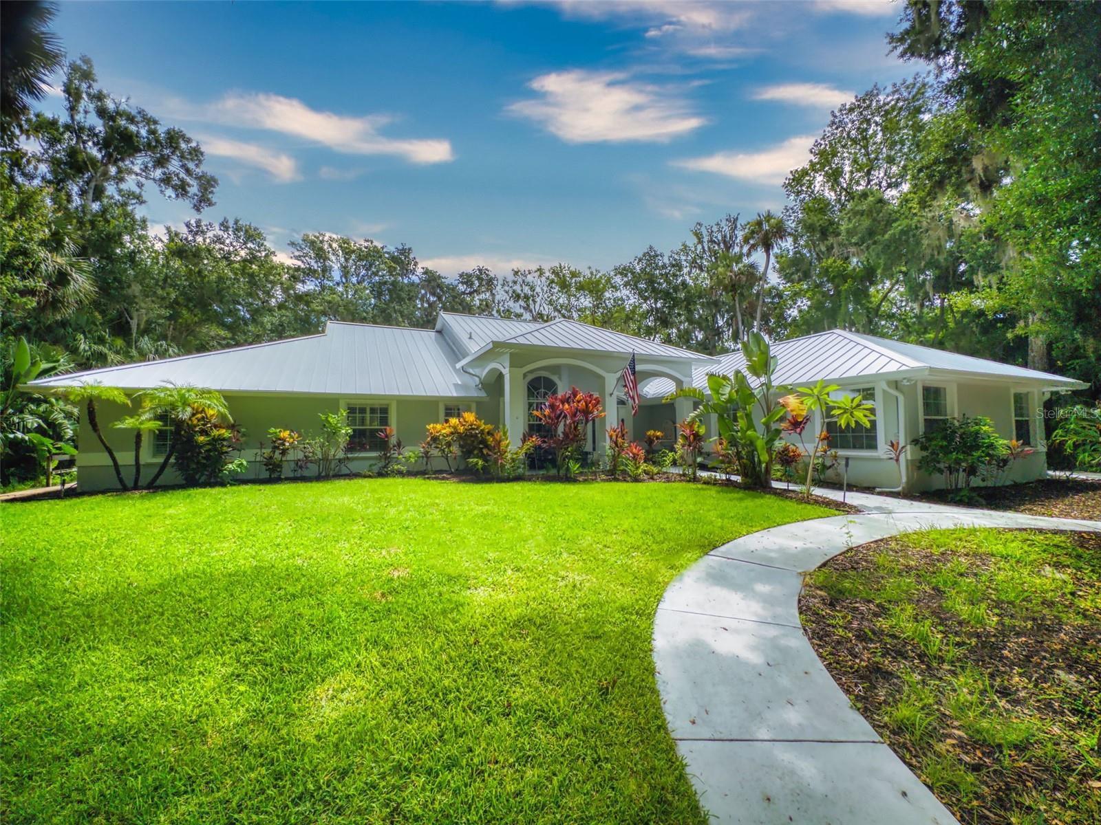 Beautiful 4 bedroom, 3 and a half bath, lakefront, pool home located in the highly desired gated community of Lake Waterford Estates in New Smyrna Beach. Lake Waterford is a 75 acre, spring fed lake perfect for boating, skiing, fishing and a number of other water sports. This spacious home sits on a 1.75 acre lot which is lush with a variety of mature trees, fruit trees and beautiful flora. Enter this home through the welcoming foyer where the eye is immediately drawn to the serene view of the tranquil lake in your own backyard. This home was designed for entertaining with a distinguished formal dining room and formal living room. The large primary bedroom, with expansive windows, letting in the beautiful views and two individual walk-in closets, will be a welcomed retreat at the end of the day. The ensuite bath comes equipped with double sinks, separate shower and a jetted garden tub. The 3 spacious guestrooms, each with ample closet space and natural light streaming through the windows, are comfortable and inviting. The hub of this amazing home is the open-concept, family room, dining nook and kitchen. This kitchen is a chef's dream with granite counter tops, stainless-steel appliances, gas stove and plenty of storage space. The kitchen opens to a dining nook and family room. As you enter the family room you are drawn to the massive natural stone fireplace. Exit the family room through custom, stained-glass french doors to your sparkling, screened-in pool and classic pavered patio deck. Sit and enjoy your morning coffee as you take in the beauty of life on the lake.
Just beyond the pool is a pavered walkway that will lead you down to the boat-house and dock. This durable dock, made of trex deck material, is equipped with electricity, water and newer boat lift. What better way to end the day than with a relaxing boat ride or simply sitting on your own dock enjoying the beauty of nature in this breathtaking setting. Other outstanding features of this exquisite home: indoor laundry room with full bath, oversized 3-car garage, whole home diesel-powered generator, outdoor storage sheds, circular driveway, central vacuum system, custom stained-glass lighting and doors, high ceilings and plantation shutters. NEW METAL ROOF 2024. Air Conditioners, Refrigerator and Hot Water Heater new in 2024. The Lake Waterford Estates community amenities include a clubhouse, tennis courts and boat ramp. This sprawling, exquisite home offers the best of Florida living. This property is conveniently located less than 10 miles to the sandy beaches of New Smyrna and about an hour to the Orlando airport. Call today to schedule an appointment to see this truly spectacular and unique home.