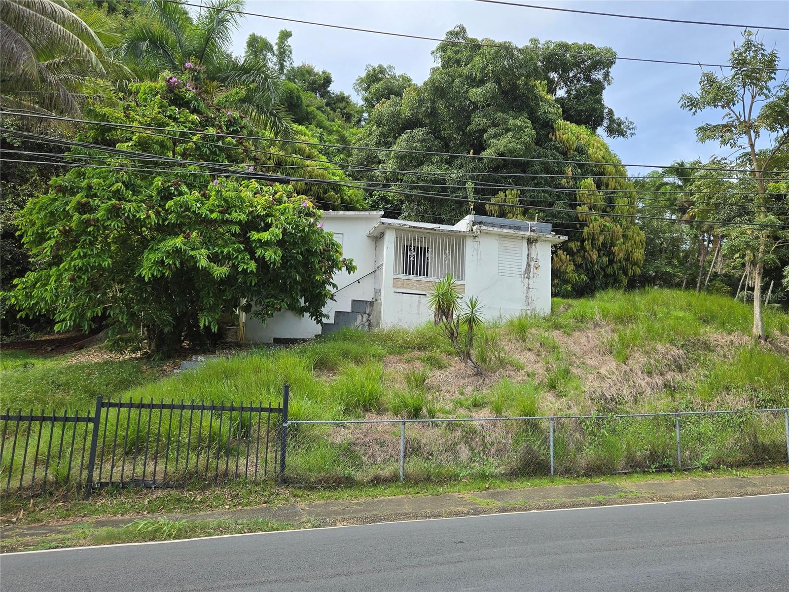 Property for sale located in the Pueblo neighborhood of Corozal, Puerto Rico. The residence features four bedrooms, one bathroom, a living room, dining area, small kitchen, terrace, carport, and balcony. It sits on a spacious lot of approximately 5,384 square meters and requires general improvements, making it an excellent opportunity for remodeling to your taste or as an investment project. Its location is strategic, just steps away from a shopping center, the town center, schools, and with easy access to Expressway 142. This property offers a combination of space, location, and great potential.