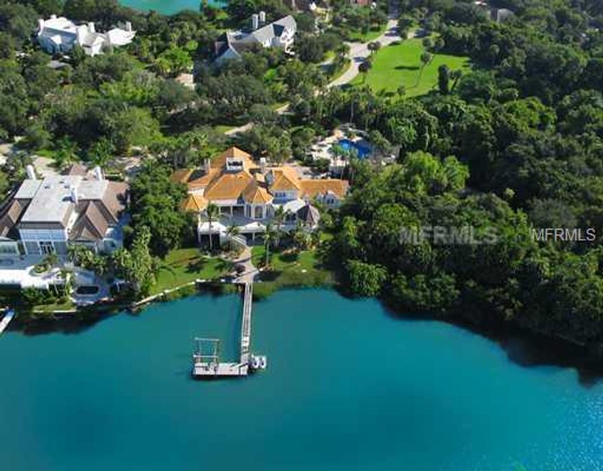 THE SELLER of this exquisite Bayfront Estate in the prestigious Oaks Club Bayside section IS VERY MOTIVATED. The Georgian style home, known as Malvern Oaks, sits graciously on a double bayfront lot with 100 feet on the bay, adjoining the gardens of historic Spanish Point. The grandeur of this home becomes apparent when entering the columned living room with its beautiful tray ceilings, the Carrera marble flooring with Verona marble accent and a hand carved Italian marble fireplace. Six French doors are leading directly out to the 60 feet long marble terrace which overlooks the private dock with boat lift for a 30 ft boat and allows for gorgeous sunset views. The dining room, right next to a separate entertainment kitchen features a Strauss crystal chandelier. The superbly appointed main kitchen offers custom crafted cabinetry with high end appliances from Wolf, Asko, Miele and Subzero, bronze fixtures and Tanzia granite counters. The family room with large arched windows overlooking the bay displays impressive millwork and an oak beamed ceiling. A knotty pine library offers quiet space for reading or relaxing by the wood burning fireplace. The master suite is of special grandeur and opens to the marble terrace. On the ground floor an additional 4,366 sq ft of airconditoned space offers amenities enhancing this exclusive lifestyle. The motor court offers room for 20 cars while the garage will hold 5 or more cars. The large, pool features a pool house outfitted with full bath, kitchen and laundry room.