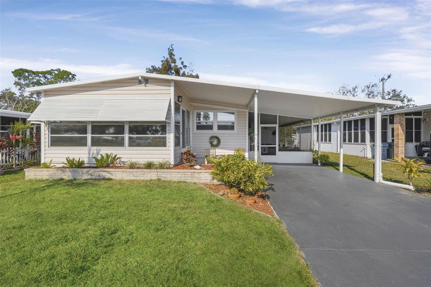 Savor your morning coffee and enjoy Florida sunrises from your Florida room with a lake view. Welcome to this lovely two-bedroom, two-bath La Casa home. The entry leads into the kitchen with newer cabinets, appliances, lighting, and ceiling fan. The adjacent dining room features a server. The comfortable living room has shiplap accenting two walls and a sliding door to the front glass-enclosed Florida room with beautiful lake views. The hallway also has shiplap walls, a utility closet, and a linen chest. The guest bedroom offers a walk-in closet, and the guest bathroom has a new vanity and commode. The primary bedroom includes shiplap accents, new raised-panel doors, and a barn door to the dressing area with a double closet, vanity, and beadboard accents. The primary bath has a walk-in shower. Upgrades include an aluminum roof-over in 2012, new A/C in 2016, new water heater in 2018, and new aluminum posts, screening, and doors for the carport lanai in 2022. This lovely home, located near the front of the park, has much to offer.