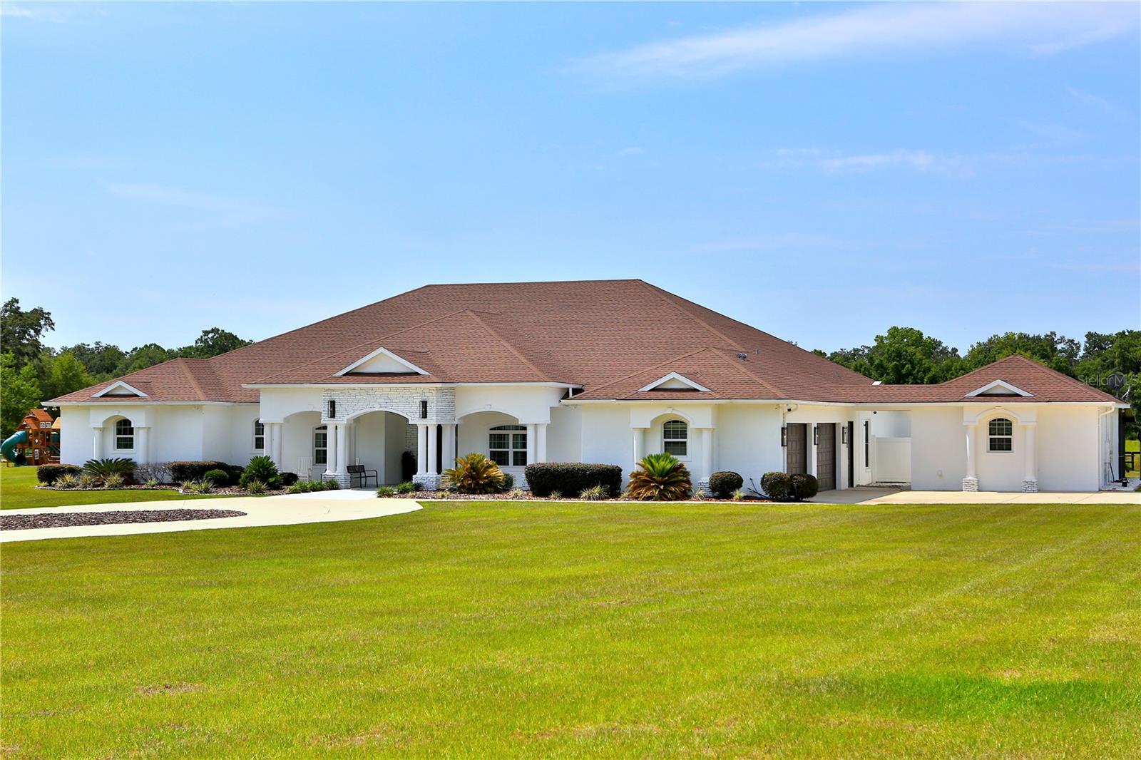 Discover a captivating estate that redefines luxury in one of northwest Ocala's most sought-after areas. Spanning over 10 acres, this extraordinary property offers an exceptional blend of elegance and seclusion, perfectly situated among premier destinations such as the Adena Golf and Country Club, Golden Ocala Golf & Equestrian Club, and the renowned World Equestrian Center. Residents will relish a dynamic lifestyle filled with world-class equestrian events, top-notch golfing, delightful dining options, shopping, and year-round festivities.
Step into the meticulously maintained main residence, where every detail epitomizes superior craftsmanship. From the grand entryway with soaring tray ceilings to the beautiful crown molding and modern light fixtures, elegance abounds. The expansive chef's kitchen is a culinary dream, featuring two islands, Brazilian marble countertops, and high-end appliances, including a gas range—perfect for both everyday cooking and entertaining.
Unwind in the cozy media room, designed for the ultimate movie experience with its projector and plush theater seating. The luxurious primary suite serves as a tranquil retreat, complete with a private sitting area featuring a cozy fireplace and direct patio access. The spa-like en-suite bath boasts a soaking tub, a walk-in shower, dual vanities, and luxurious marble flooring.
Step outside to the sprawling patio that opens to an impressive indoor pool area, a true entertainer's paradise equipped with a fireplace and TV, as well as a sparkling pool and spa. Adjacent to the main living area, a well-appointed covered outdoor kitchen simplifies outdoor dining, making al fresco meals a delight.
For guests or extra family, a delightful guest cottage that reflects the elegance of the main home features its own screened-in patio. Equestrian lovers will value the option to construct a barn on the current concrete pad, accompanied by extensive pastures that can be customized for your horses' requirements.
This estate embodies a lifestyle of unparalleled luxury and functionality, offering the perfect sanctuary for those who seek the ultimate equestrian living experience. Come and see for yourself the extraordinary possibilities that await!
