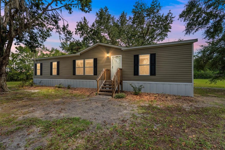 One or more photo(s) has been virtually staged. Built in 2022, this thoughtfully designed 3 bedroom, 2 bath manufactured home offers comfort, efficiency, and room to grow on 3.73 acres of peaceful countryside. With 1,456 square feet of living space, this home features a desirable split floor plan with a spacious living room that flows into the dining area and kitchen, perfect for everyday living and entertaining. The kitchen is bright and functional, while the primary suite provides a true retreat with ample space and privacy including a large walk in closet. Additional bedrooms are well-sized and share a second full bath. Recent upgrades include a water treatment system, new well pump, and new ceiling fans in every room for added comfort. Durable vinyl flooring runs throughout the main living areas and baths for easy maintenance. Automatic pet door leads to a small fenced area for animals. Enjoy the outdoors with a fully fenced yard and separate fenced area for pets, a pole barn/workshop ideal for parking equipment or tackling projects, and plenty of space under the shade of mature trees. Located just minutes from town yet tucked away in a quiet, country setting, this home is move-in ready and waiting for you. Just 30 minutes to Gainesville or Palatka and 15 minutes to Melrose and Hawthorne. Schedule a showing today!