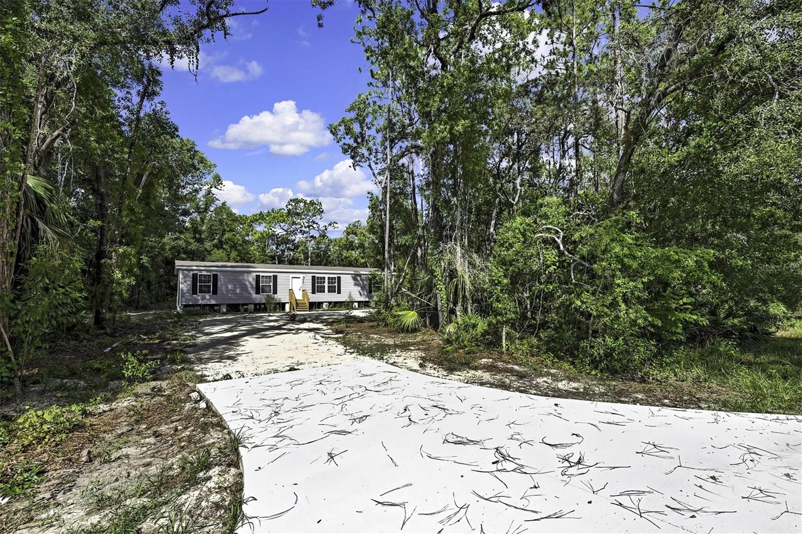 This brand new & never lived in 3/2 Champion Prime manufactured home is nestled on almost an acre of land with paved road access, offering the perfect blend of comfort and privacy. Each bedroom features a generous walk-in closet, ensuring plenty of storage space. The master bedroom includes a double-sink vanity in the en-suite bathroom for added convenience, plus a large walk-in shower. The open floorplan is filled with natural light, making it ideal for both family gatherings and quiet relaxation. In addition, there is a spacious & separate den that can even be used as a home office or bedroom. The modern kitchen features stainless steel appliances, white cabinetry, and an island. The large lot has plenty of room for all your toys & gardening. This home is move-in ready, all set for you & your family to enjoy! EVERYTHING is brand new & never used; well, septic, home, appliances, AC, etc. All of this is being offered for an amazing price, so schedule your showing today!