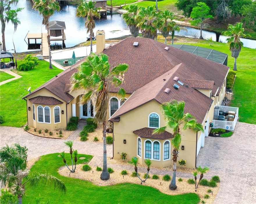 With 154 feet of direct lake frontage in gorgeous Preston Cove on the Clermont Chain of Lakes, this is the lakefront home you’ve been looking for! Expansive 24-foot-wide, 8-foot-high double-pane tinted sliding glass doors create a seamless indoor-outdoor lifestyle with sweeping lake views and effortless access to the pool, large backyard, boat dock, outdoor patio with speakers, beach, fire pit, and lake. Beautifully upgraded throughout, the home showcases extensive custom architectural details and premium finishes. Step through the leaded glass double front doors and notice extensive crown, chair rail, dental, and picture-frame molding, PERGO flooring, a three-sided wood-burning fireplace, upgraded daylight lighting, and soaring 12-foot ceilings that complement the fully remodeled kitchen featuring quartz countertops, a massive 10’ x 5’ island with seating and storage, stainless-steel appliances, and a separate coffee station. All windows throughout the home are double-paned and tinted for enhanced energy efficiency, comfort, and privacy.
The five-bedroom floor plan features a bright and spacious 16’ x 29’ first-floor primary suite, a private downstairs guest suite, and two additional downstairs bedrooms, including one with a lake view. Upstairs, a bonus room includes an additional bedroom suite with a full bath. A flexible multi-use area is currently configured as an office, while the 13’ x 30’ Florida room features a full-size refrigerator, wet bar, wine rack, and versatile space for dining, entertaining, and relaxing.
Outdoor living is elevated to a resort-style experience with a complete six-speaker integrated high-end stereo entertainment system, two large 4K poolside TVs, professional landscaping, home and dock lighting, power-operated west-facing sun/wind/privacy and cooling solar shades, and extensive exterior electrical outlets. The screened pool area features newly sealed and sanded pavers, a never-used baby-gate fencing system, a large covered patio, and a heated pool and spa.
Outside, enjoy a brick-paved entertaining area with outdoor speakers, a flexible gathering space, and a sugar-sand beach with a fire pit. The boat dock features an upgraded 6,000-pound boat lift, an automatic power cover, and complete dock electrical and water supply connections.
Major system upgrades include a 40-year architectural roof, multi-zone HVAC systems for individualized comfort, solar-powered roof ventilation fans, and a fully upgraded security system with motion and glass-break sensors, with optional monitoring available. A large built-out attic storage area with stair access is conveniently located above the laundry room.
Additional highlights include an oversized three-car garage with three garage doors and dual connecting driveways, 10 professionally mounted TVs, a full irrigation system, professional curbing and landscaping accents, a rock-perimeter termite barrier with transferable termite bond, and extensive custom upgrades throughout. This exceptional lakefront showpiece offers seamless indoor-outdoor living, resort-style amenities, and thoughtfully designed upgrades throughout.
Preston Cove is a beautifully maintained community featuring large lots, mature trees, a private boat ramp, park, playground, and low HOA fees.