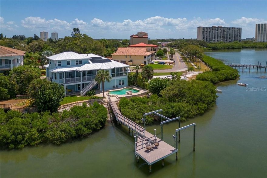 Enjoy sweeping panoramic views of Boca Ciega Bay from this beautiful Key West style home—from the moment you walk in the door! Centrally located on the edge of South Pasadena, this 5 bedroom, 4 bath 3876 sq feet waterfront home features cathedral ceilings, a split floor plan with separate formal dining room, an open kitchen with granite countertops, walk-in pantry, breakfast bar and two screened balconies for alfresco dining with spectacular sunset views overlooking 101 ft of Intracoastal waterfront. The master suite has a large walk-in closet and en suite bathroom with double sinks, separate walk-in shower and garden tub. The backyard features a fenced in dog run, saltwater pool with waterfall feature and also a private launch area for a kayak or paddleboard—perfect for enjoying the ultimate Florida waterfront lifestyle! Also recently new elevator, luxury vinyl flooring, composite decking and steps, 2 new AC systems (2021) and new electric panel (2021). Plus hurricane impact windows throughout, solar panels for whole house electric, metal roof and an oversized garage with separate workshop area and parking for up to 5 cars PLUS a boat with trailer. Located just minutes away from St Pete Beach. Also near parks, playgrounds, restaurants, shopping and a short drive to vibrant downtown St Petersburg. A must see—make an appointment today! Room Feature: Linen Closet In Bath (Primary Bedroom).