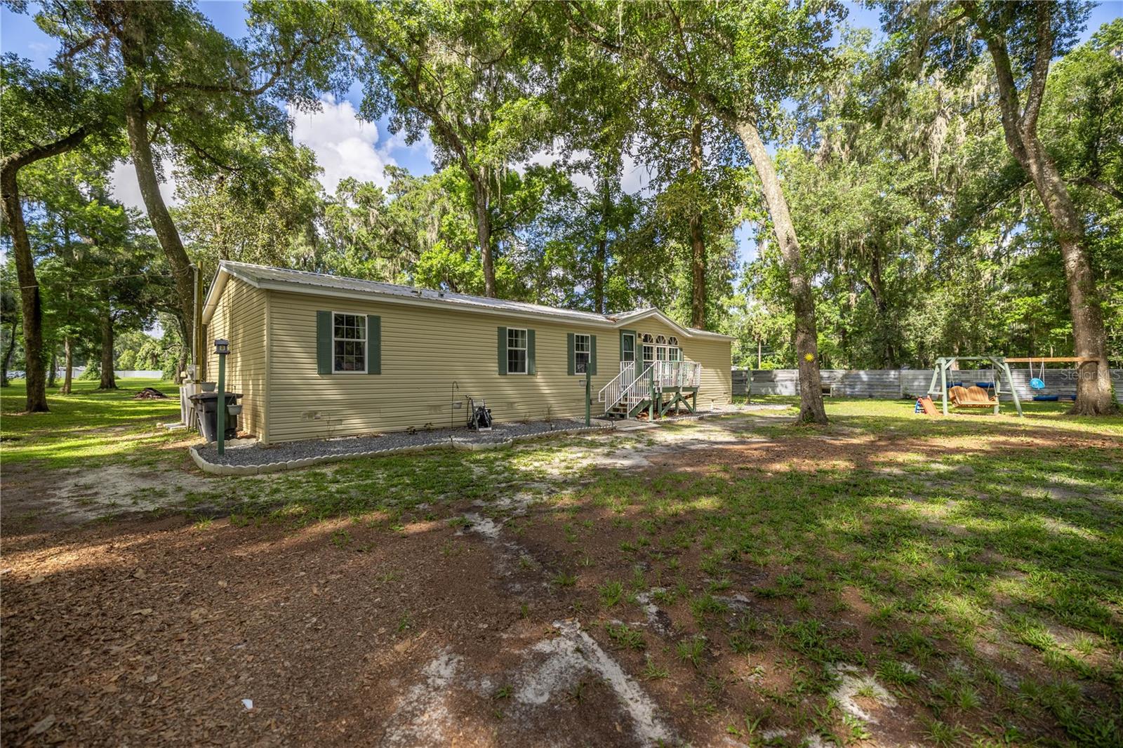 Buyer Financing Fell Through. Come and take a look!! *Priced to Sell Quickly* Discover this hidden gem, perfect blend of privacy, comfort, and rural charm with this serene 3.0-acre fully fenced (metal privacy fence) property. Whether you're looking for a spacious family home or a private retreat, this peaceful haven offers both. Nestled among mature trees that provide natural shade and a picturesque backdrop. The 2006 mobile home features five generously sized bedrooms and two full bathrooms, offering ample space for family, guests, or a home office. The home boasts separate living and dining area, as well as a breakfast room, centered around a beautiful fireplace, creating a warm and inviting atmosphere. Luxury vinyl plank flooring flows throughout the main living spaces while the bedrooms offer cozy carpeting for added comfort. Recent upgrades include a 2021 A/C unit, ensuring year-round comfort and peace of mind. Additional features include an inside laundry room, a water softener system, and a spacious 12x20 shed equipped with worktables, electricity, and its own breaker box—perfect for storage, hobbies, or a dedicated workspace. Zoned A1, this property allows for a flexible rural lifestyle and opens the door to various agricultural opportunities, including the ability to keep animals—making it an ideal setting for those dreaming of a hobby farm. A new refrigerator and dishwasher will be installed prior to Closing. Convenient to both Ocala and Gainesville. No HOA fees. Don’t miss this opportunity to own a piece of tranquility. Schedule your private showing today and experience the serenity this property has to offer. Bring the whole family! CASH and CONVENTIONAL.