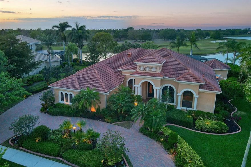 Live in the heart of Lakewood Ranch, on this premier street in this beautiful one-story Lakewood Ranch Country Club home. Portmarnock is one of the best streets in the LWR community. Perfectly positioned to deliver long lake and golf course views, this Arthur Rutenberg custom built 3-bed, 4.5-bath home embodies the essence of true indoor/outdoor Florida living. The brick paver circular drive and walkway give way to the welcoming covered entry featuring accustom wood, glass, and wrought iron double door. Once inside, one is struck by the tranquil pool, lake, and golf course views just beyond. Crown moldings, tray ceilings, stone detail, designer cabinetry, and neutral tile floors are just some of the features that make this home something special. The living room includes art niches, a stone gas fireplace, and pocketing sliding doors to the lanai. The adjacent dining room is made for entertaining or large family gatherings and features a wet bar between the dining room and the kitchen that includes a wine refrigerator, two beverage drawers, and an ice maker. The kitchen boasts custom wood cabinetry, granite countertops, two dishwashers, bar seating, two pantries, high-end stainless steel appliances including a large center island with a 6-burner Dacor gas cooktop, warming drawer, Sub-Zero refrigerator, and a climate-controlled wine room that holds 300+ bottles. The adjacent breakfast nook, with a large aquarium window, adds natural light to the kitchen and adjacent family room. The family room includes two sets of sliding pocket glass doors that open to the lanai, outdoor kitchen, and pool area. The grand bonus/game room also features sliding glass doors to the lanai, a wood-paneled vaulted ceiling, and a wet bar with a beverage cooler and a microwave. The owner's suite is complete with a private sitting room, fireplace, private courtyard, two walk-in closets, and a luxurious bathroom with dual vanities, a walk in shower, a jacuzzi Roman tub, a water closet, and a sauna. There are 2 private guest bedrooms each complete with an en-suite bathroom as well as a well-appointed office trimmed in beautiful wood details and shelving. Relax by the alluring pool and spa, enjoy a fire, or al fresco dining in the outdoor kitchen. A fabulous state of the art Heston grille and griddle, Lynx sink and cabinets that light with soft close drawers. When exploring this award-winning community, you will find two amazing clubhouses, a fitness center, two pools, tennis, pickleball courts and a basketball court in addition to the pristine golf courses. Lakewood Ranch has been ranked as one of the best-selling master planned communities in the nation. Lakewood Ranch Country Club is conveniently located near Lakewood Ranch Main Street, the new Waterside Place, and shopping or dining at UTC, easy access to I-75, and a short drive to the beautiful beaches.
