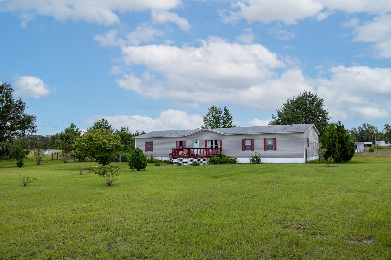 Enjoy country life on 1.25 acres in Archer. 4/3 Fleetwood Eagle Trace model Mobile Home with 2280 sq ft. Rectangular shaped lot, home sits in the middle with an inviting front porch to relax on. Walk into this wonderful home in the formal living room & feel the openness with the Laminate flooring continuing throughout the home. Next is the family room with large, spacious kitchen. Center island has a breakfast bar & bookcase along with an area for a table. Plenty of counter space & storage with laundry room to back door & expansive covered back porch. Back porch has stairs & a ramp for easy access. The land is pretty with fruit trees (two lemon & Japanese Plum) & a scattering of other various trees throughout the property. Storage unit for lawn equipment & plenty of room in the yard for a fire pit area, playground, Cornhole & Horseshoe pit. Life is great in this quiet & peaceful place in paradise.