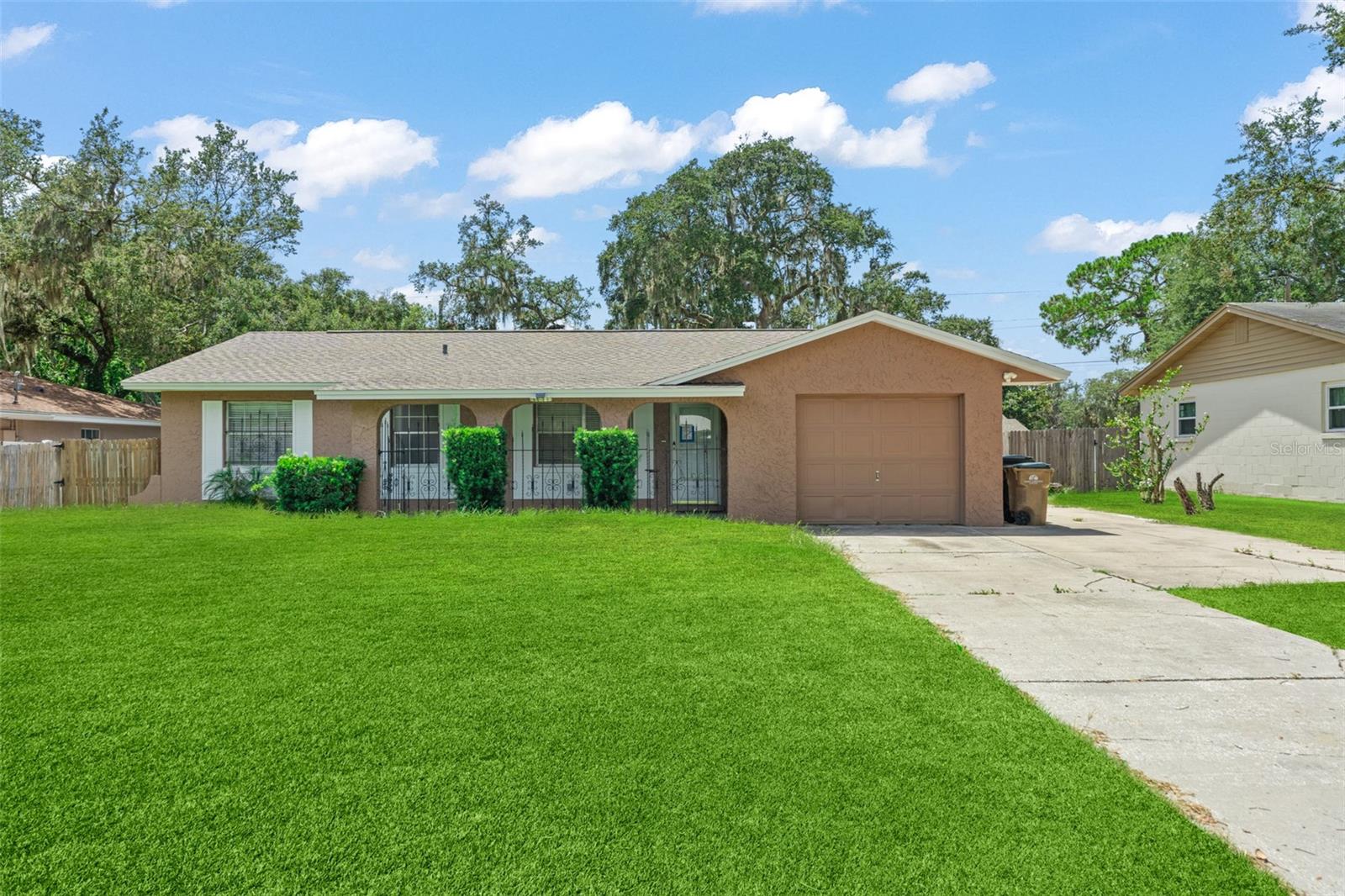 **This property qualifies for a closing cost credit up to $4,000 through the Seller’s preferred lender.**This single-family home is situated on almost a quarter-acre lot in beautiful Mount Dora. Offering just under 1,200 sq ft of living space, it has 3 bedrooms, 2 bathrooms, and a 1-car garage with an extra-wide driveway for added convenience. The fenced front porch provides a space to unwind or welcome guests. Inside, you’re greeted by a open living room that offers a peek into the dining area and kitchen, all finished with easy-care laminate flooring. Enjoy meals in the dining room with a view of the large backyard through sliding glass doors, creating a seamless indoor-outdoor flow. The kitchen features stone countertops, brown cabinetry, black and stainless steel appliances, a breakfast bar, and additional counter and cabinet space—perfect for entertaining or everyday living. All three bedrooms are located to the left of the home and feature tile flooring and built-in closets. The guest bathroom includes a tub/shower combo, while the primary suite offers a private ensuite bath with a walk-in shower enclosed by glass sliding doors. Step out back to a wooden deck, ideal for outdoor gatherings, overlooking a fully fenced backyard—a true blank canvas ready for your landscaping dreams. The included shed provides extra storage space, and the expansive lot offers room to expand, garden, or play. This home combines comfort, functionality, and space to grow—perfect for first-time buyers or anyone seeking a peaceful setting close to the charm of downtown Mount Dora.