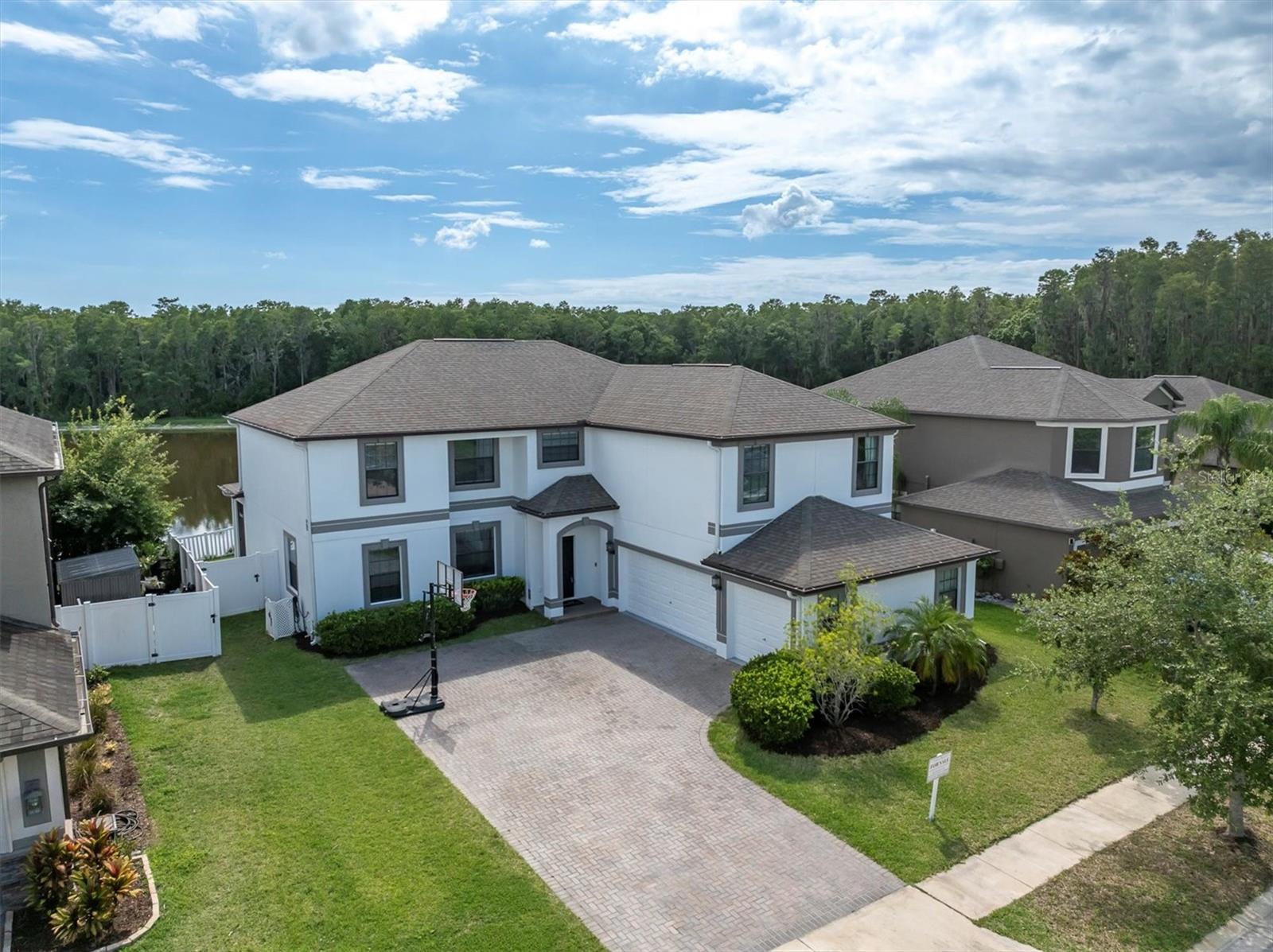 Still searching for that unicorn home in Trinity with jaw-dropping lake views, space to spread out, and a layout that actually makes sense? Found it. Welcome to 12135 Crestridge Loop, where your 5-bedroom, 4-bathroom, 3-car garage dreams collide with peace, privacy, and panoramic water views. This is not your average boxy floor plan. Step inside and you’re greeted by a two-story foyer that says, yes, this house has presence. To your left, a dining room ready for hosting (or transforming into a second living room if your entertaining style is more charcuterie than charger plates). To your right? A huge guest suite on the main level with its own full bath—perfect for in-laws, visiting friends, or a really lucky teenager. And then—there’s the kitchen. Not just big. Not just pretty. This is chef-level meets HGTV glow-up. New Italian marble countertops? Yes. Two built-in flush refrigerators? Also yes. Gas range, floating shelves, stainless steel hood, and custom lighting? You bet. A contrasting island the size of an aircraft carrier? Basically. It’s all open to a spacious family room with views that stop people mid-sentence. Wildlife lovers, bring your binoculars—deer, turkeys, turtles, and bald eagles make regular cameos. Outside, the backyard is fully fenced with sleek vinyl fencing and plenty of space to add a pool (just check out the example in the photos). And if you like the idea of sipping coffee while staring at the lake in your pajamas with no rear neighbors in sight? This one's for you. Head upstairs and things just keep getting better. The primary suite is a whole wing of the house, with two walk-in closets, room for a reading nook or office, and a spa-inspired bath with soaking tub, separate shower, dual vanities, and a private water closet. Three more bedrooms share a full bath, and the bonus rooms have the opportunity for a bedroom, guest room, office, craft room and more! It even has it's own ensuite and a separate room—ideal for guests, teens, or a quiet media zone. Let’s talk practicality: no carpet anywhere, upstairs laundry room (because laundry shouldn’t require stairs), new whole-house alkaline water system, salt-free purification system, custom hurricane shutters, and zero flood zone = peace of mind. Newly painted inside and out, with a well-maintained A/C and biannual servicing. Whole-house gutters just added, too. The home is less than 10 years old and tucked into the gated, sidewalk-lined community of Trinity Preserve, with no CDD fees, low HOA dues, underground utilities, and surprisingly low insurance. And in case you’re wondering—yes, this beauty handled the recent hurricanes like a champ, without power loss or damage. So yes, the market may be slower, but this home? It’s not your average listing. It’s got space, style, strength, and a view that’ll outshine the competition any day of the week. Come see it for yourself and bring your imagination—we’ve already got the space for it. Virtual tour, video walkthrough, and floor plan: bit.ly/12135Crestridge