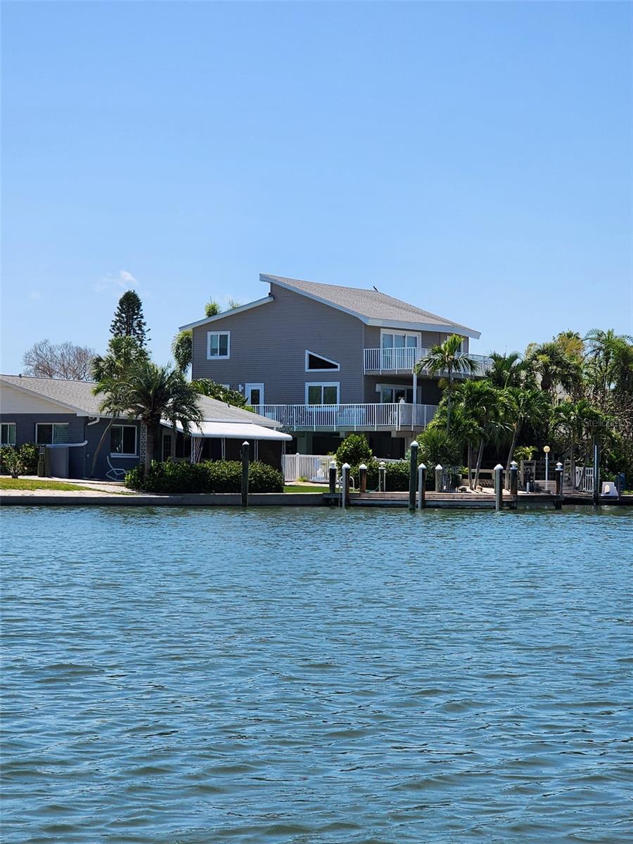 A rare find! This elevated 2,516 SF home has everything you want to live the ultimate Florida lifestyle. This home is an elegant 3BR/2.5BA and has a generous amount of outdoor space to enjoy the west-facing sunset views. The home sits on a waterfront lot, with DEEP WATER, suitable for large boat and sailboats. Enter the house from the 2nd floor and you'll immediately notice the recently renovated modern kitchen. The white European style cabinets, appliances and high-end stone counters give off a very stylish first impression. The space is wide open into the living and dining room and you have soaring 18' ceilings and large windows over the water. The spacious owner's suite is on this floor and also has a very nicely updated ensuite. You'll find a laundry room conveniently tucked away on the 2nd level. Head up to the 3rd floor to another large living space with windows and sliders allowing a full view of the water out to the beach. There are also 2 generously sized bedrooms and a shared full bath. Both 2nd and 3rd floors have decks that run the full length of the house overlooking the water! There are water views from EVERY room in the house. Outside, there is entertainment space everywhere. The dock has a lift on one side, mooring on the other on deep, protected water. The owner used to park a 50' boat on this dock! The pool is perfectly placed and has has easy access to the built in bar and entertainment area. This is the PERFECT setup to host large crowds with plenty of room to roam. There are 2 separate garages and areas throughout the base level for storage. The home was designed to withstand whatever Florida delivers and sustained minimal damage to the bottom floor from recent hurricanes, no damage to living space. Windows are all impact, except for picture window in living room. Seller will have roof replaced prior to closing. Easy to show, call for an appointment to see this