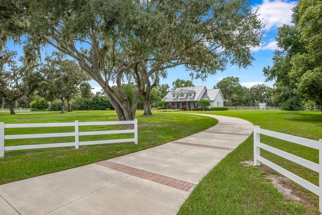 FISHHAWK VICINITY – YOU CAN HAVE IT ALL! Welcome to a truly picturesque 5.77-acre private estate offering the perfect blend of peace, privacy, and practicality—with NO HOA, NO CDD, and located in a top-rated school district! This impressive property boasts nearly 4,000 SqFt of living space in the beautifully updated 5-bed, 4.5-bath main home, PLUS an additional 2,400 SqFt in a fully insulated and air-conditioned 40x60 metal building with 4 garage bays—perfect for a workshop, home business, storage, or guest space. Unforgettable Curb appeal stuns with grand oak trees and a circular drive, leading to a home filled with over $350K in recent upgrades, including a 2022 metal roof, 2023 well + saltwater pool system, and 2024 whole-home generator. Inside, enjoy an open-concept layout with formal living and dining rooms, a cozy electric fireplace, and a chef’s dream kitchen featuring GE Café appliances, oversized island, white shaker cabinetry, a wine/coffee bar, and endless storage. The split-plan layout offers a luxurious primary suite on one side, two additional main-floor bedrooms sharing a renovated bath, and two more bedrooms with full bath upstairs—plus walk-in attic storage. Outside, relax on the massive covered/screened lanai overlooking your private saltwater pool and beyond, a fully fenced backyard. Need space for toys or tools? The detached 60 X 40 metal building includes 4 bay doors, RV hookups, a full bath, screened lanai, and A/C. Additional features: 2-car attached garage + 2-car carport (2025), smart home tech, security system, 10-zone irrigation, and pet-safe fencing. With no deed restrictions, there’s plenty of room for your RV, boat, animals, hobbies, or business gear. All of this just 30 minutes to Tampa or Lakeland, and minutes to FishHawk, Plant City, Brandon, and top-tier shopping. Don’t miss this rare opportunity—schedule your private tour today!