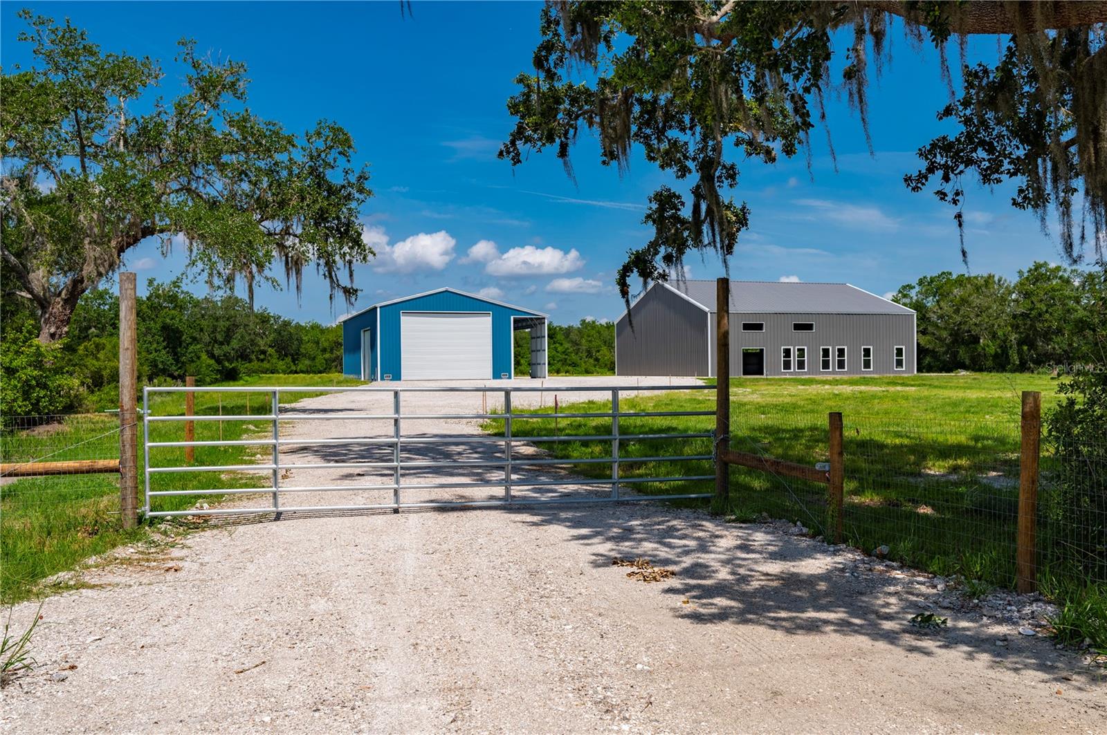 Looking for land, space, and a head start on a Barndominium? This 5+ acre property in scenic DeSoto County offers all that and more.
Set behind a gated entrance, the partially finished barndominium is 60’x80’ and is thoughtfully designed with a 10-foot wraparound porch-perfect for soaking in the peaceful views of your private pond and scattered oaks. The interior is a blank canvas, ready for your personal layout and finishing touches. With electric and well already in place, much of the heavy lifting is done. Need extra space? A seperate 30x70 detached building with multiple roll-up doors and an 8’x70’ covered overhang offers storage for RVs, boats, equipment, or whatever your lifestyle demands. The property is fenced, with open pasture and beautiful perimeter trees-ideal for animals, family play, or simply enjoying the wide-open space. Zoned for Residential Mixed Use, this is your opportunity to build the life you want. Tucked between Hwy 70 and Hwy 72, you're just minutes from Arcadia and within easy reach of Port Charlotte, Sarasota, and Bradenton-rural charm without sacrificing convenience. If you've been searching for flexibility, freedom, and a property with potential already in motion-this is it.
