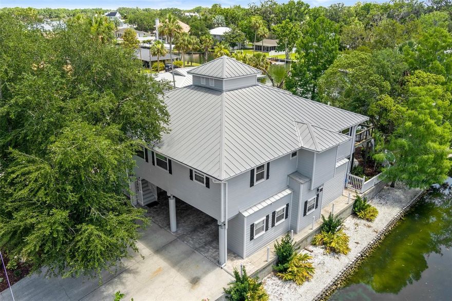 This updated waterfront stilt (DID NOT FLOOD) home in Crystal River is a rare find, nestled on a spring-fed cove with approximately 329 feet of waterfront. Enjoy natural springs, scenic views of Kings Bay, and effortless access to the Gulf. Exterior features include a covered 10,000 lb boat lift and dock, a pool, fenced yard, and gravel pad for boat trailer storage. Located just off Fort Island Trail near The Plantation, the home sits just outside the Crystal River city limits—allowing for convenient golf cart access to everything the area has to offer. Designed with entertaining in mind, the expansive open kitchen is a dream for home chefs, featuring a 9-foot maple butcher block island and a 48” professional Bertazzoni range. A formal dining room with fireplace and a large Brazilian Ipe wood deck off the breakfast area extend the living and dining spaces outdoors. Rich heart pine floors add warmth and character throughout the home, while the sunroom—framed with floor-to-ceiling windows—fills the interior with light and captures tranquil water views. The primary suite has been beautifully renovated to include an oversized shower, soaking tub, and an attached laundry for ultimate convenience. The upper level includes an additional bedroom with en-suite bathroom, a half-bath, sunroom, office, dining room, kitchen, and breakfast area. Downstairs, an elevator leads to two more bedrooms, a full bath, a den, and a large utility room with hookups for a second laundry and abundant storage. The carport beneath the home features enclosed workshops and multiple closets for all your recreational gear. Structurally engineered with concrete piers anchored to bedrock and elevated 19 feet above sea level, this home is built to last. Bring your boats, kayaks, family, and friends—and experience the best of Florida’s Nature Coast in this exceptional Crystal River retreat.