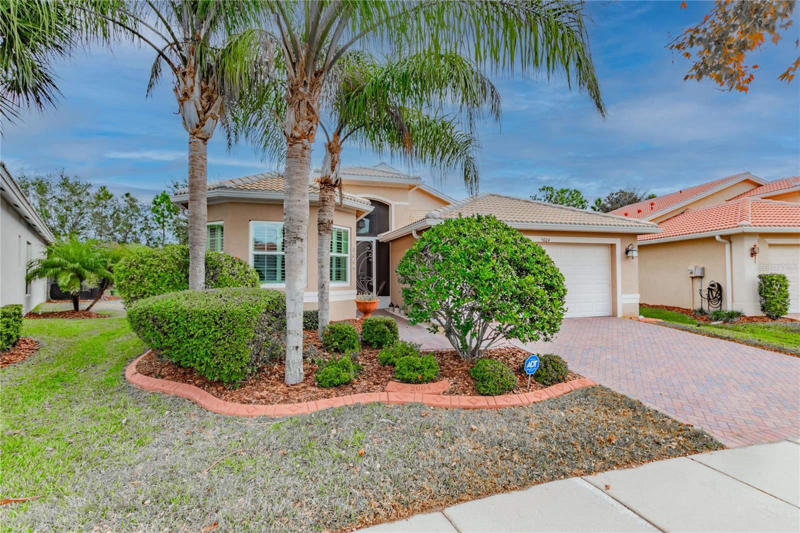 One or more photo(s) has been virtually staged. Welcome to this immaculate Roma model home in Valencia Lakes, the Greater Tampa Bay’s premier 55+ community, where luxury, comfort, and lifestyle converge. This immaculate residence offers 3 spacious bedrooms plus a versatile den that can easily serve as a fourth bedroom, along with 3 full bathrooms and a 2-car garage. From the moment you arrive, the impressive curb appeal sets the tone with lush landscaping, custom curbing, a brick paver driveway, a barrel tile roof, and a beautiful bay window. Step inside through the screened front entry into a spacious foyer highlighted by soaring 14-foot coffered ceilings and diagonal-laid tile flooring that extends throughout the entire home—no carpet in sight. The formal living and dining areas are perfect for entertaining, while the open-concept family room seamlessly connects to the gourmet kitchen and leads to an extended screened lanai through impact glass sliders. This private outdoor retreat features upgraded tile flooring and is the ideal spot to enjoy a serene Florida sunrise. The eat-in kitchen is a chef’s dream, featuring 42" maple cabinets with under- and over-cabinet lighting, a lazy Susan, quartz countertops, a designer ceramic backsplash, a reverse osmosis system, and top-of-the-line stainless steel appliances including a French door refrigerator and Bosch dishwasher. The primary suite is your private sanctuary, complete with a bay window sitting area, tray ceiling, and two walk-in closets with custom built-ins. The en-suite bathroom exudes spa-like elegance, showcasing a frameless walk-in shower with a built-in seat, a Roman bathtub, dual vanities with quartz countertops, and raised-panel white cabinetry. Secondary bedrooms are located away from the primary suite, offering privacy for guests. The den, with double six-panel doors, adds flexibility for a home office or extra sleeping space. Bathrooms two and three are beautifully appointed with Corian counters, banjo tops, and white cabinetry. The laundry room offers convenience with a large-capacity Samsung washer and dryer, utility sink, and overhead storage cabinets. Upgrades throughout the home include freshly painted interiors, a water softener system, impact glass windows and doors, ceiling fans, custom window treatments, built-in closet organizers, storm shade at the entry, pull-down attic stairs, epoxy-coated garage floor, built-in storage cabinets in the garage, and a new HVAC system installed in 2021. Living in Valencia Lakes means access to a 40,000-square-foot clubhouse, resort-style pools, a bistro, tennis, pickleball, bocce ball, walking paths, a full calendar of events, clubs, live shows, educational seminars, and more. HOA fees cover clubhouse membership, lawn maintenance, irrigation, high-speed internet, cable TV, and security system monitoring. This home is more than a place to live—it’s a lifestyle. Don’t miss your chance to experience the best in 55+ living. Schedule your private showing today and start living your best life.