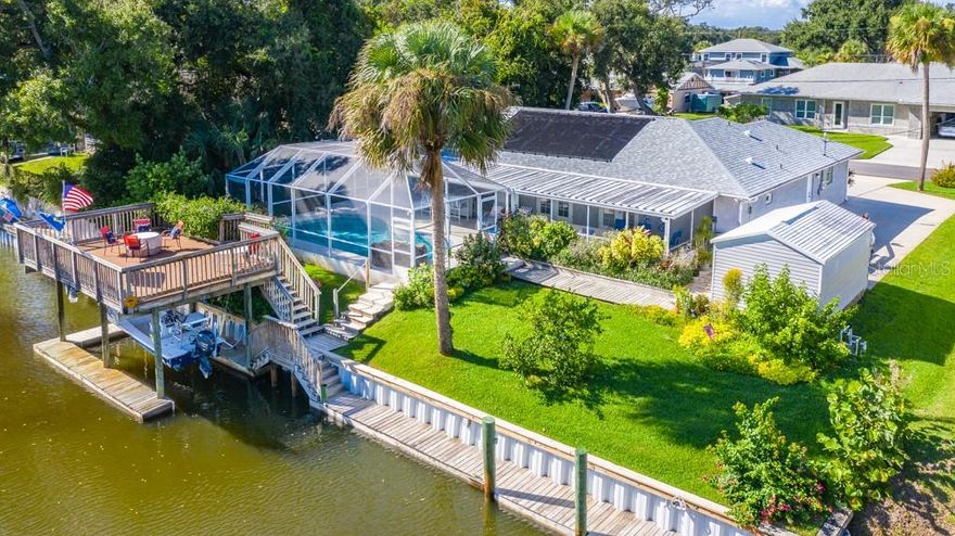 This stunning, immaculate home has it all - this is the one! Come see this spectacular waterfront resort-style pool home with private dock and covered boat lift. Featuring a heated, screened, private pool with waterfall and very large covered lanai with bar - plus a large waterfront deck - you'll have plenty of room for outdoor living, be it entertaining family and friends or relaxing privately, all while surrounded by lush, colorful tropical landscaping (including a certified monarch butterfly garden). The pool is dual heated (solar and electric) and is a salt system, not chlorine. The 100' of waterfront has a seawall in excellent condition, dock, and covered boat lift with the Intracoastal Waterway just at the end of your canal (very near the end of a no-wake zone for added convenience). Remodeled just 4 years ago, this home features 3 bedrooms and 2 bathrooms and a sunny open floor plan with contemporary coastal decor, including wood-look tile, plantation shutters, new hurricane-rated windows and more. In addition to the 2-car garage, the home has a large shed and paved boat/RV parking with 30 amp service and septic hookup. This home is on a lovely, quiet dead-end street, is not in a flood zone and has a termite bond. Roof is brand new in 2019 and AC is 3 years old; has city water and a regularly serviced septic system. ;Water: City