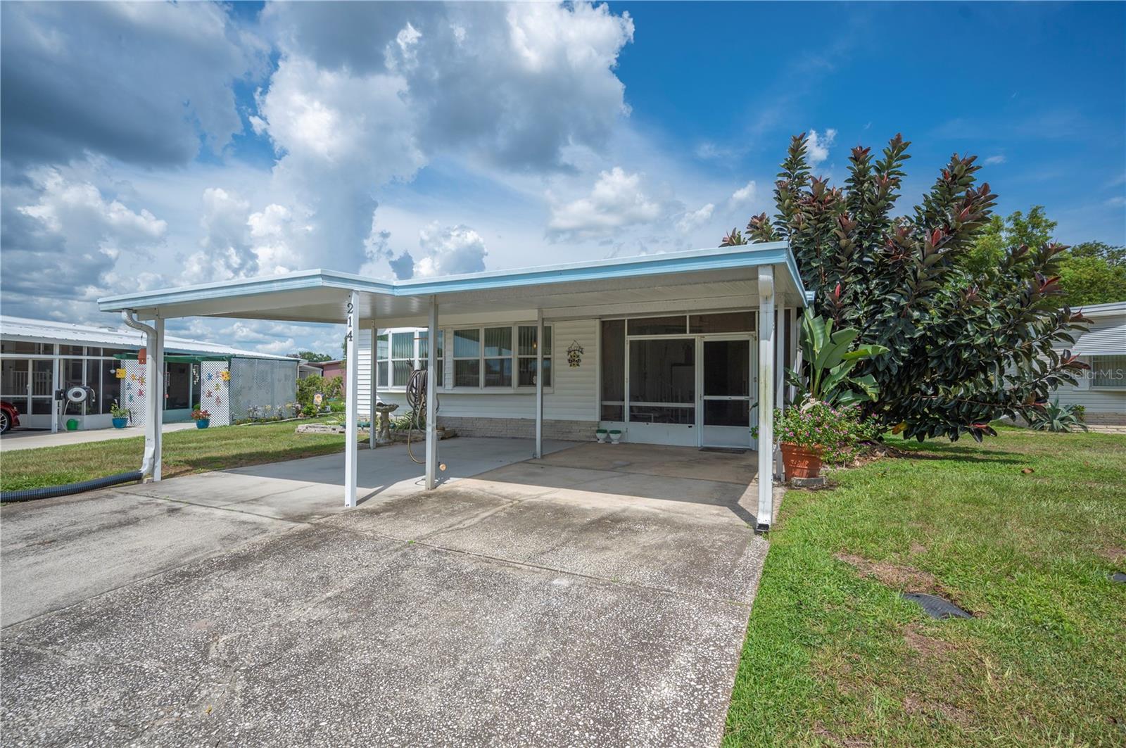 Welcome to Citrus Woods Estates—an affordable and active 55+ community where you OWN your land (no lot rent!) This spacious 2-bedroom, 2-bathroom home is full of thoughtful features and extra space for relaxed Florida living. Outside, you’ll find an oversized driveway, a 2-car carport with charging space for your golf cart. A large, screened and covered porch offers the perfect place to unwind or entertain guests. Behind the porch is a utility room/workshop with the washer and dryer—ideal for hobbies and extra storage. Step inside to a bright and inviting living space with updated windows and sliding doors, plus the charming bay windows that let in tons of natural light. The kitchen includes a closet pantry, while the dining area features built-in cabinetry for even more storage. The primary suite is a true retreat with sliding doors to a private screened patio, an enormous walk-in closet, a dedicated office space with built-in desk, and a full en suite bathroom. The guest bedroom includes sliding doors that open to the covered porch, and the hall bath offers extra linen storage. Citrus Woods Estates offers an unbeatable lifestyle with an ultra-low HOA of just $710/year and amenities including a heated pool, shuffleboard courts, clubhouse with a rec room, library, and year-round community activities. Rentals allowed after one year of ownership. This home has been pre-inspected to give you peace of mind! With so many homes on the market, don’t miss the one that delivers value, flexibility, and lifestyle—schedule your private showing today!