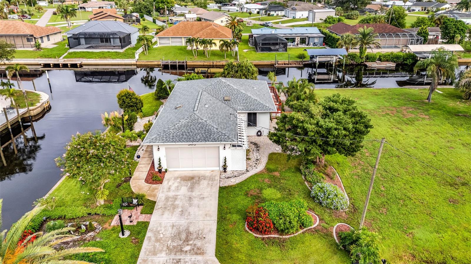 This one-of-a-kind 3-bedroom, 3-bathroom waterfront home in the desirable Harbour Heights community is designed to maximize its stunning canal and Peace River views. Situated on a corner lot with 200 feet of saltwater canal frontage, a concrete seawall, and private dock, the home captures the water from the moment you step through the front door, creating a truly unique setting for Florida living.
The open great room and dining area provide plenty of natural light and flexible living space. The kitchen features abundant counter space, a center island, glass tile backsplash, stainless vent hood, and built-in microwave. The primary suite offers a walk-in closet and sliding doors that open to an office/bonus room with panoramic river views. Two guest bedrooms also feature private baths—one with its own entrance that is perfect for visitors or extended family, and also presents an excellent income opportunity as a private rental suite. An indoor laundry room with built-in shelving adds convenience and functionality to daily living.
Outdoor living shines with a wraparound porch, rear patio, and multiple areas for relaxing or entertaining. The front porch provides a serene spot overlooking the canal and views of the Peace River, while a welcoming front garden adds charm to the entry. In back, a private herb garden with a French drain creates a peaceful retreat and a touch of sustainability. The property is enhanced with Bahama shutters for shade and storm protection. Here, you can enjoy the best of both worlds—the calm waters of the Peace River, ideal for kayaking, wildlife watching, and fishing for largemouth bass, catfish, snook, and tarpon, combined with direct passage through Charlotte Harbor to the Gulf of Mexico for world-class saltwater fishing, boating, and open-water adventures.
Additional highlights include a new roof (2022), HVAC system (2025), two storage sheds, and a spacious 2-car garage. Located on a quiet dead-end street in a friendly neighborhood, this home combines peace and privacy with convenient access to downtown Punta Gorda, I-75, shopping, dining, and parks. With no HOA or CDD fees, this distinctive property offers a rare chance to enjoy the best of Florida’s waterfront lifestyle.