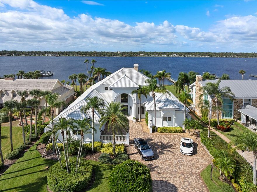 Welcome to 846 Riverside Drive, a stunning expression of timeless elegance and refined waterfront living along the coveted Ormond Beach Intracoastal Waterway. Designed by R. Norman Stoehr, founder of Forum Architecture & Interior Design, Inc. (now retired), this masterpiece exemplifies thoughtful craftsmanship and architectural grace. Beyond the gated entry and pavered motorcourt, manicured grounds frame this exquisite four-bedroom, four-and-a-half-bath residence—a home designed to impress at every turn. A grand two-story foyer crowned by a brilliant crystal chandelier sets the tone for sophistication. Marble tile floors lead you through an interior defined in equal measure by luxury and warmth. The formal living and dining rooms are separated by a double-sided marble fireplace—a striking centerpiece that enhances the flow of light and panoramic river views beyond. Each of the four bedrooms, two upstairs and two on the main floor, is a private retreat featuring an en suite bath,

walk-in closet, and oak hardwood floors. The primary suite, located on the ground level, offers serene views and direct access to the wraparound Saltillo-tiled veranda - an inviting space to enjoy morning coffee or an evening cordial at sunset. The en suite bathroom features Jacob Delafon fixtures, a jetted soaking tub, dual vanities, and a glass-enclosed shower with body sprayers and an eyebrow window. The primary closet offers built-in cabinetry and drawers to maximize storage, along with its own electrified garment carousel.
The main floor also includes a formal office with etched-glass French doors, a motif echoed in the primary suite entry and the glass balustrade ascending to the second story. Between the formal dining room and the spacious family room lies a bar area crowned by a domed ceiling, hand-painted with a blue sky and doves. Three sliding glass doors in the family room provide easy access to the rear gardens and wraparound veranda, where multiple al fresco seating areas are accented by sculptural art and elegant fountains.
The resort-style amenities continue with a sparkling in-ground pool and attached infinity-edge spa. The property extends gracefully to a private covered dock, completing the perfect setting for leisurely afternoons of fishing or sunbathing along the river.
The gourmet eat-in kitchen includes a large center island with prep sink, double wall ovens, dual four-burner gas cooktops, dishwasher, microwave, and a GE Monogram side-by-side refrigerator, ensuring both beauty and functionality. It is the ideal space for entertaining family and friends.
Rounding out the first floor is a spacious laundry area, a secondary bedroom with en suite bath, under-stair storage, access to the three-car garage with 13-foot ceilings, vented interlocking raised floor tiles, and a mirrored octagonal half-bath for guests.
Ascending the solid oak staircase, you'll find two additional bedrooms, each with access to the second-story balcony featuring concrete balustrades and breathtaking views of the backyard and Intracoastal coastline. This level also offers attic access, a laundry chute, and a 17' x 5.5' conditioned storage room.
Every detail of this home from the handcrafted finishes and exceptional millwork to the LED-lit stairs, decorative tray ceilings, and etched-glass elements reflects a commitment to quality and timeless sophistication.
This home is more than a residence—it is a statement of coastal grace and refined Florida living!