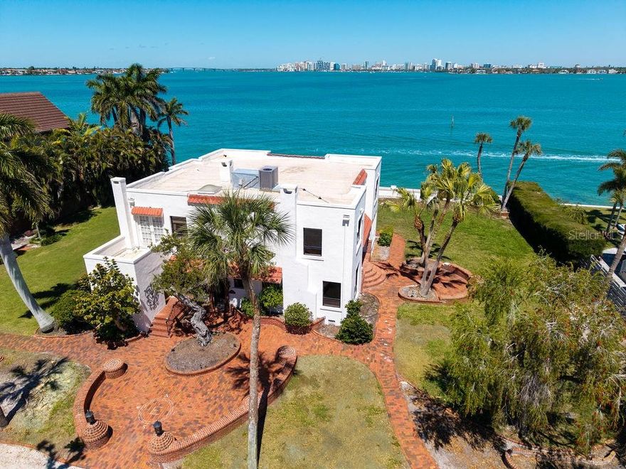 Tucked away on highly sought-after Bay Island, just over the North Siesta Key Bridge, 679 Norsota Way is a rare and extraordinary opportunity to own a piece of Sarasota’s architectural history or create something entirely new. Built in 1926, this Mediterranean Revival estate with Spanish Colonial influences sits gracefully on an expansive 2/3-acre lot, offering timeless character, generous scale, and unmatched potential. With 150 feet of deep water bayfront, the homesite is one of the largest on Bay Island's coveted northern edge.

The 3,788 sqft two-story residence features 4 bedrooms, 3.5 bathrooms, a dedicated office, and a flexible bonus room, with all bedrooms thoughtfully positioned on the second level. The primary suite is exceptionally spacious and captures breathtaking views overlooking Sarasota Bay, the Ringling Bridge, and the downtown skyline, a daily backdrop that defines true coastal living.

Original details and soft historic charm are present throughout, providing a warm and inviting foundation ready to be reimagined. The home has been flood remediated but not remodeled, offering a clean slate for restoration or renovation while preserving its architectural integrity.

Importantly, the property is not historically designated, presenting a rare level of flexibility. For those seeking new construction, this exceptional 2/3-acre homesite offers the opportunity to start fresh without the constraints of an HOA or significant building restrictions, an increasingly uncommon advantage in such a premier location. No deed restritions or grand oaks constrain construction.

Beyond the main residence, a secondary structure provides a two-car garage and hobby space, ideal for storage, creative pursuits, or future customization. Perfectly positioned just 10 minutes to downtown Sarasota and 5 minutes to the beach, this property blends privacy, proximity, and prestige in one of the area’s most coveted neighborhoods.