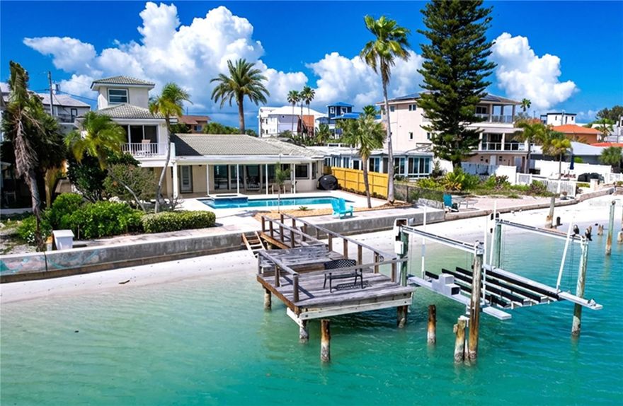 Welcome to 7711 Bayshore Drive, where the best of waterfront living meets effortless beach access in the heart of Treasure Island. Perfectly positioned on the Blind Pass Waterway, this exceptional 4-bedroom, 4-bath home offers protected boating waters, direct Gulf access with no bridges, and the rare convenience of being just approximately 500 feet from the white sands of the Gulf and the Sunset Beach boardwalk.

Originally built in 1949 and completely rebuilt in 1995, the home spans nearly 3,000 square feet of living space and showcases a spacious open floor plan designed to maximize panoramic water views. The living and dining areas flow seamlessly to a large covered lanai, creating the ideal setting for indoor-outdoor living and entertaining.

The waterfront outdoor space is truly special, featuring a 16x32 gas-heated pool and spa, a beautifully landscaped yard, and a 45-foot dock with water and electric offering excellent fishing and immediate boating access to both the Gulf and Intracoastal Waterway. A unique stairway leads down to a sandy private beach along the waterway during lower tides, adding to the property’s charm.

Upstairs, the primary suite enjoys stunning water views from a private balcony and includes a generous walk-in closet and additional flex space ideal for a desk or reading area.

Additional highlights include a 3-car garage with over 1,500 square feet of garage, hobby, and storage space, as well as a large front yard with room for RV or additional parking.

Recent updates include a new seawall cap (2021), updated electrical, select window replacements, an updated kitchen, and a brand-new gas fireplace installed in the living room in 2026.

This is a rare opportunity to own a well-built waterfront home offering boating, fishing, and beach access all in one of Treasure Island’s most desirable locations.