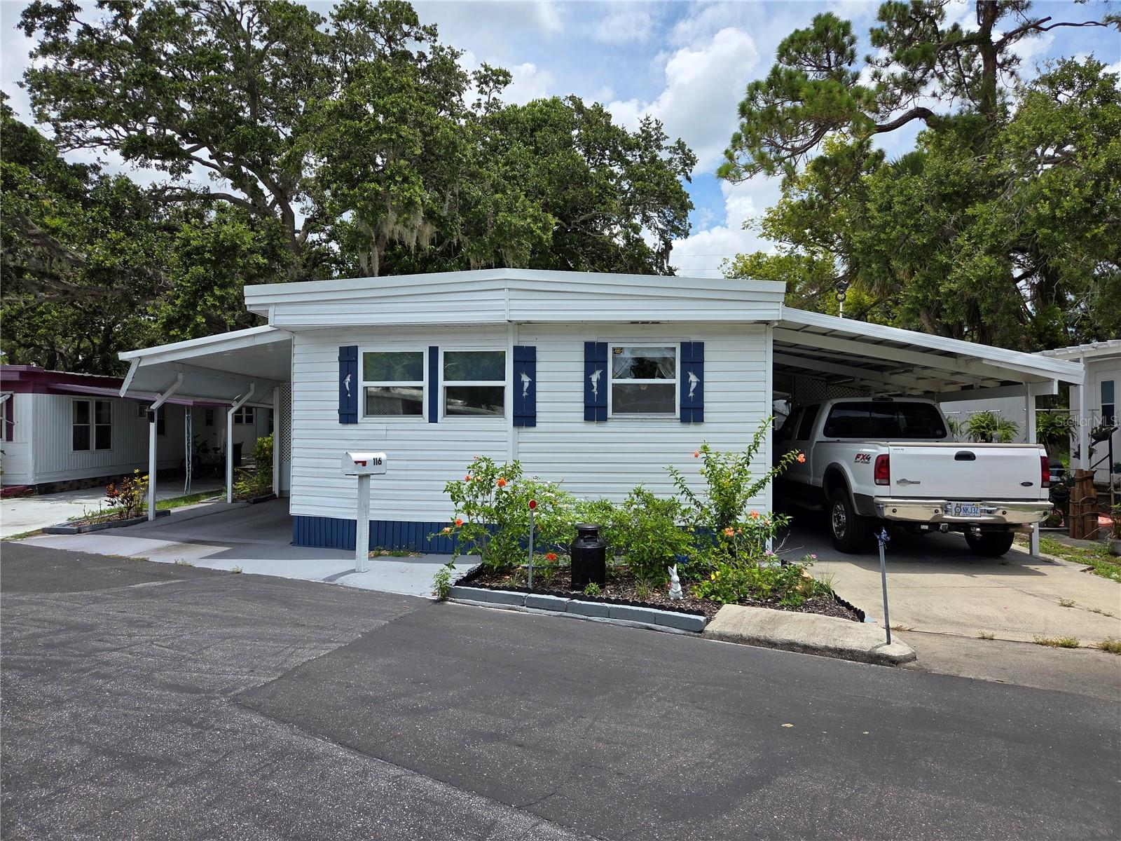 This 2 bed 2 bath home is located in Melody Gardens a resident owned community. The home has 2 carports, roof over, vinyl siding, 2 storage sheds, screen room, covered backyard patio and a central HVAC system (with heat pump). The refrigerator, washer & dryer are 5 years old. The microwave, couches and tv is 4 years old. The roof was installed in 2024. The home comes fully furnished. The living room is open with a dining area. There is a galley kitchen located at the front of the home. The spare bedroom is located off of the living room. The main bathroom is located in the hallway leading to the master bedroom. The master bedroom has a half bath. Community Amenities include: Swimming Pool, Shuffleboard Court, Activities & a Clubhouse. The HOA fee is $180 a month.