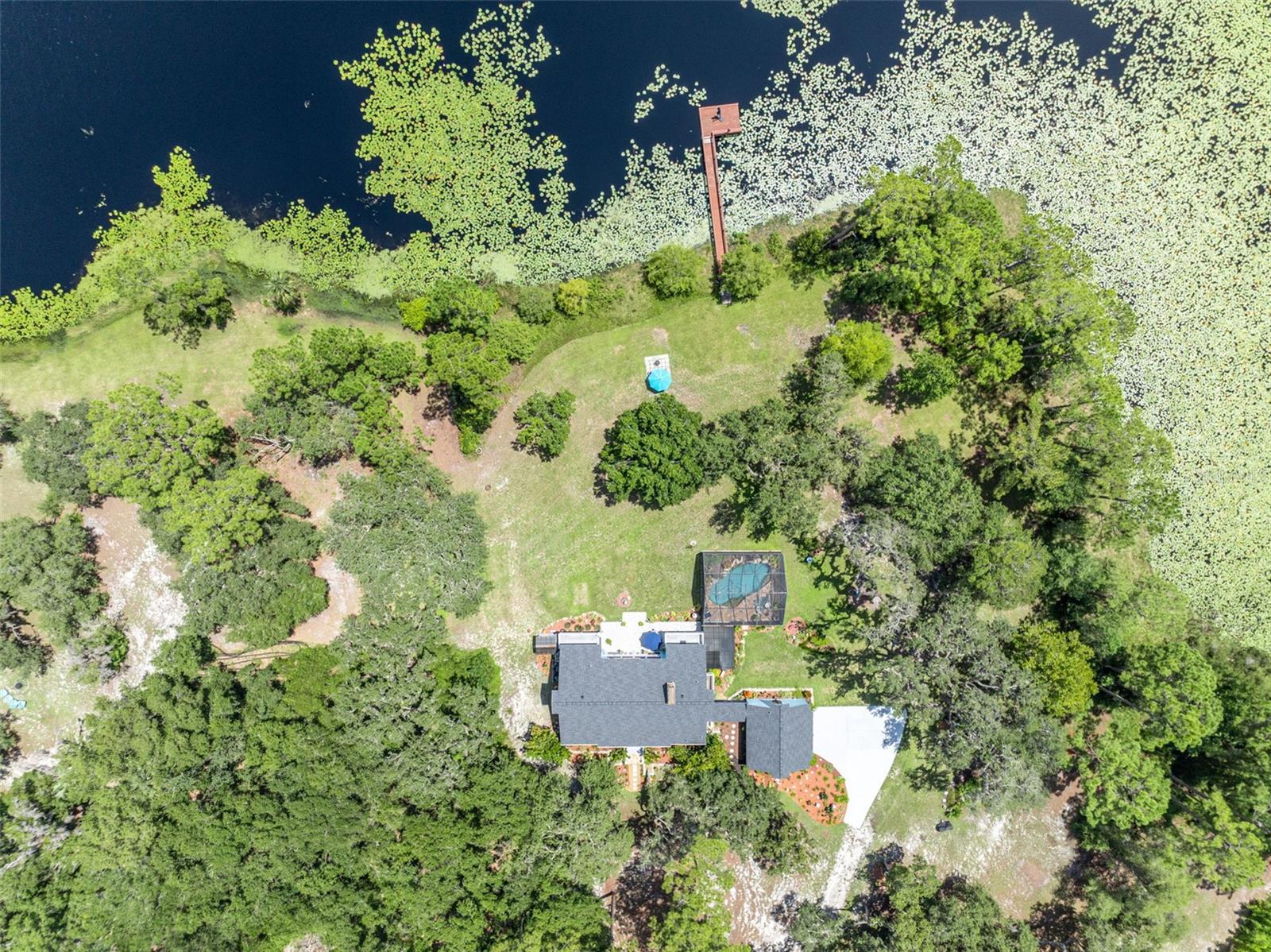 One-of-a-kind lakefront estate with a pool, and private dock on 6.41 acres! This property offers peaceful Florida living at its finest. Surrounded by timeless oaks and overlooking tranquil Jenkins Pond, the property is designed for both relaxation and recreation. From fishing off your dock to enjoying your heated pool or relaxing on the screened lanai, every day feels like a retreat. Inside, you’ll find 3,402 square feet of living space with soaring cathedral ceilings, expansive windows, and French doors that fill the home with natural light while showcasing exceptional lake views. The open great room features a wood-burning fireplace and flows seamlessly into the dining room, which sits just off the kitchen. The beautifully updated kitchen offers granite countertops, a new dishwasher, an island, soft-close cabinets, and a breakfast bar. The layout is designed with space for everyone, offering five bedrooms and three bathrooms in total. Two bedrooms are located downstairs and three upstairs. The owner’s suite is upstairs and is a private sanctuary with its own fireplace, two balconies, and dual walk-in closets. Upstairs, two of the bedrooms, open through French doors to a balcony overlooking the water, where you can enjoy beautiful morning sunrises! The detached two-car garage has a covered walkway that provides easy access to the kitchen, adding everyday convenience to the homes thoughtful design. Recent updates include a new roof (2022), septic tank and drain field (2022), new pavers, a hot water heater (2025), and so much more! Unbeatable location, just minutes to I-4, shopping, dining, and under 40 minutes to Orlando and the beaches. Showings are by appointment only. Come experience this exceptional estate, you won’t want to leave paradise once you see it for yourself!