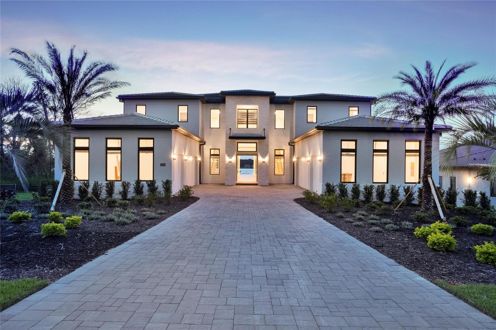 STAND OUT FROM THE ORIDNARY and elevate your lifestyle into the breathtaking realm of Bella Collina! Introducing a newly constructed luxury lakefront residence highly positioned on an expansive acre-plus lot in the exclusive Estates section of the community. Overlooking the serene shores of Lake Sienna, this exceptional home offers panoramic water views, sophisticated interior finishes, and an ultra-impressive outdoor living space designed for both relaxation and entertaining. This is more than just a home, it’s a statement of purpose and meaning. From the moment you step through the covered entry, you’re met with dramatic architectural elements including double floating staircases, a soaring two-story open concept gathering space and uninterrupted sightlines to captivating lake views. The main level has been thoughtfully designed for both convenience and everyday living and features a grand, open concept living, dining, and kitchen area, a luxurious primary suite with lake views, a secondary en-suite bedroom, a versatile flex room, powder bath, large laundry room, and a practical drop zone off one of two oversized three-car garages. Upstairs, a walkway bridge for added privacy separates three additional en-suite bedrooms, a private home office, and a spacious loft and media room prewired with multiple Cat 6 outlets for today’s connected lifestyle. What truly sets this home apart is the outdoor living area with a spacious travertine deck, high ceiling covered lanai, fully equipped summer kitchen, gas fireplace, and a dedicated pool bath and shower - all framed by picturesque water views. The custom-designed infinity-edge pool is flanked by two raised pedestal mounts ideal for fire bowls or water features. A multi-person heated spa and sun shelf invite tranquil moments under the sun.
A stately cascading staircase leads to a lower-level retreat with artificial turf and aluminum fencing—prime for a fire pit or lounging area. A second terraced area below takes you down to a sprawling backyard with over 140 feet of shoreline. Planning to bring your boat? This is one of the select properties that can accommodate a private dock. Completed in April and awaiting your personal touch, this home is an extraordinary opportunity to own in one of Florida’s most prestigious guard-gated, golf communities. Bella Collina spans over 2000 acres and is truly a one-of-a-kind compelling setting from awe-inspiring scenery and topography to a collection of striking homes of distinction offering an unmatched lifestyle for those wanting luxury lakefront living. Highlights of the features and amenities include a Tuscan-inspired hilltop village showcasing a world-class 75,000 square foot clubhouse, ballroom, full-service spa, restaurants and bars. There are also tennis, pickleball courts, a state-of-the-art fitness center, resort-style pool w/ lap lanes, dog park and even a heli-pad. It is conveniently located within easy reach of Orlando International Airport, downtown Orlando, the town centers of Winter Garden, Clermont, Minneola, and the highly anticipated Olympus Project in Wellness Way. Outdoor enthusiasts will love the West Orange Trail just a few miles away. Top rated schools, hospitals, shopping, and dining are close by. Theme parks are a short easy drive... Whether you're seeking an upscale, active way of life filled with social aspects and a variety of choice activities, or a peaceful haven of refined living, 15121 Pendio delivers it all.