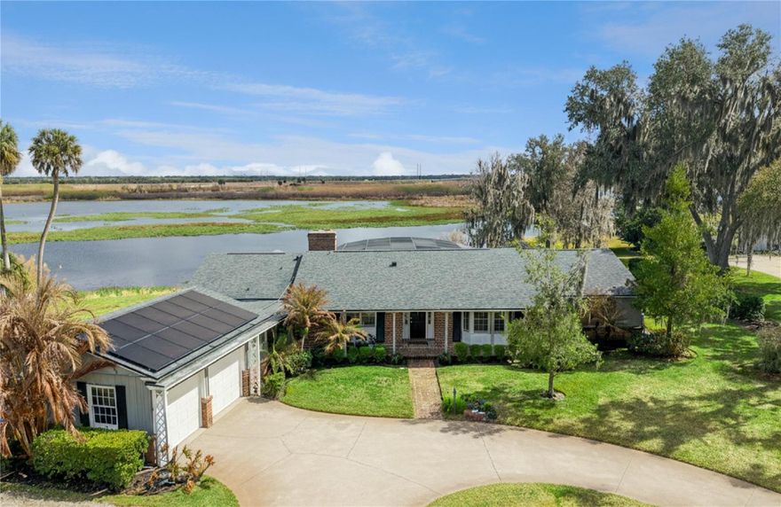 Welcome to this stunningly renovated home on a pristine 2/3-acre waterfront lot on the St. John’s River. Complete with 175 feet of frontage and a private dock. This 4-bedroom, 3.5-bath custom-built home perfectly blends true Old Florida charm with updated mid-century style. Nestled within a small community among canopy oak trees and an abundance of nature, this residence boasts sweeping views and is just a short boat ride to Lake Monroe and downtown Sanford. ** The owners completed extensive renovations in 2020 while retaining the home's original character, featuring warm Savannah brick accents and terrazzo floors. ** Upon entering, you are swept away by breathtaking water views. The Great Room connects you to outdoors through expansive double sliding glass doors accented with custom Belgium linen drapes. Outside a large covered patio offers several areas to unwind by the sparkling pool, which features new limestone pavers and a refinished rich interior under a screen enclosure. Stroll down to the dock to enjoy serene miles of views, cast a fishing line, or launch a boat for trips to Lake Monroe or Lake Jessup. ** Inside, the Great Room includes separate living and dining areas set before a curved brick wood-burning fireplace and rich Cherry wood beams. The remodeled kitchen is a masterpiece of detail, from the rich blue cabinets with custom lighting to the Bianco Dolomite marble countertops and brass-finished exhaust hood. It is fully equipped with hidden organizers, pull-out accessory trays, wine racks, a beverage refrigerator, and a pull-out coffee bar. Behind the kitchen sits an updated laundry with matching cabinetry and 3 utility closets.**Major updates include a rewiring and new electrical panel in 2020, a new roof in 2020, and a new hot water heater in 2023.** The north side of the home is ideal as an in-law suite or guest wing, featuring a separate entrance, a large bedroom, a private bath, and access to an enormous sunroom flooded with light through oversized windows and new retractable electric solar shades. ** On the opposite side of the home, you’ll find an updated office with wood floors, custom built-ins, and modern pocket doors for privacy. All three bedrooms feature ceiling fans and terrazzo floors, while the master suite offers two large glass windows overlooking the pool and river.** The renovated master bath includes recessed lighting, a glass-enclosed shower with dual heads, and a custom vanity with under-cabinet lights. A dedicated on-demand hot water heater is located in the master walk-in closet, which also features new organizers. Modern amenities for energy efficiency include seller owned solar panels, additional plug in and wiring for a generator, spray foam insulation, and new impact resistant picture windows. The property is rounded out by a detached garage with room for all your toys and a circular driveway for ample parking. Make your appointment today to see this one-of-a-kind waterfront property.