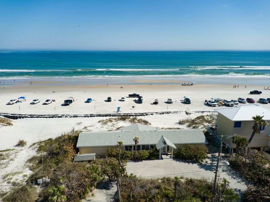 Oceanfront, ocean views, ocean access. Welcome to an extraordinary opportunity to own a true gem in the heart of New Smyrna Beach's most exclusive and sought-after area, the Oceanfront Boardwalk. This stunning residence is more than just a home; it’s a lifestyle. Perched directly on the sand with unparalleled views of the Atlantic Ocean, this property invites you to step off your back deck and sink your toes into the beach, making every day a seaside escape. This exceptional coastal retreat boasts three spacious bedrooms and three full bathrooms, with two of the bedrooms designed as luxurious master suites, each offering its own breathtaking ocean views completing your private retreat. Built on pilon construction with impact-rated windows, this home is designed for both durability and peace of mind. This home is as modern as it is charming. Set on a rare double lot, the property features a sweeping circular paver driveway, providing ample parking, and an additional outdoor storage building for all your coastal essentials. The layout has been thoughtfully designed to maximize both privacy and comfort, while the open concept living spaces seamlessly blend indoor and outdoor living. Every room features panoramic ocean views. Imagine mornings spent watching the sunrise from your deck, afternoons strolling along the beach, and evenings entertaining guests with the ocean as your backdrop. Location is everything, and this home delivers. Just a short walk to vibrant Flagler Avenue, where you’ll find an array of boutique shops, fine dining, and lively events. A quick golf cart ride takes you to Publix or the charming Canal Street district, offering the perfect blend of convenience and coastal charm. This is more than a home—it’s an opportunity to own a piece of paradise in one of Florida’s most desirable beachside communities. Properties like this are incredibly rare, and the opportunity to own a double-lot oceanfront property in this prime location is truly a once in a lifetime opportunity. Don't miss your chance to experience the epitome of coastal living. Schedule your private showing today and let this oceanfront sanctuary take your breath away. Make all offers known, as this is an opportunity you won’t want to pass up. (To be clear- This is a special short term rental zoning district which provides for rentals with NO MINIMUM REQUIREMENTS)