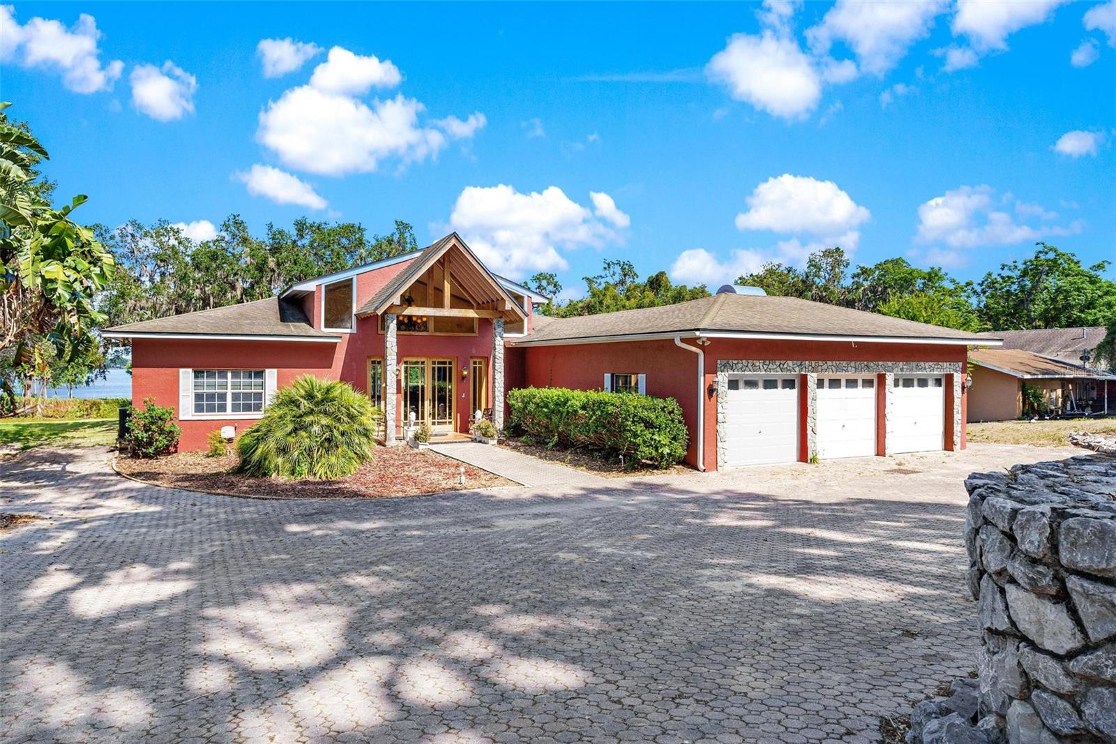One or more photo(s) has been virtually staged. One-of-a-Kind Lakefront Home on the Chain of Lakes! Discover luxury lakefront living in this custom-built 5-bedroom, 4.2-bath home on nearly an acre with 100 ft of shoreline on Lake Griffin. With over 4,500 sq ft of living space, this home features a spacious open floor plan, soaring ceilings, and rich engineered hardwood flooring throughout the main areas. Enter through the decorative tiled foyer into the formal living room with skylights, leading to an expansive kitchen and family room. The chef’s kitchen includes cherry wood cabinets with glass fronts, granite countertops, a large eat-in bar, walk-in pantry, and a wet bar—butler's counter—perfect for entertaining. Enjoy stunning lake views from the bright family and dining areas, which open to a 58x10 covered porch. Three of the five bedrooms have private en-suite baths, and there's a 15x13 office/den with a walk-in closet and exterior access. The spacious laundry room offers built-ins, a sink, closet, and private water closet with outdoor entry. This home also features dual HVAC systems, two tankless water heaters, and a spacious 29x20 three-car garage with four overhead doors and electric openers. Below the home, you'll find a finished 33x28 game room/mancave, a 28x18 workshop, and a 54x11 brick paver patio for entertaining or relaxing. Outside, enjoy the beautifully treed property and a covered boat dock with electric hoist and water—ideal for boating, fishing, or soaking in lakefront serenity. This truly unique home offers unmatched space, style, and waterfront lifestyle. Enjoy the day exploring the Harris Chain and the Ocklawaha River leading to Silver Springs & The St. Johns River. Call today to schedule your private showing!