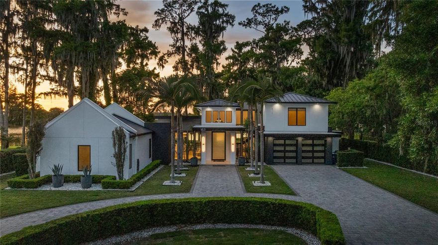 Under contract-accepting backup offers. Set on over half an acre along the shores of Lake Maitland in the heart of the coveted Vias, this exceptional residence by Modish Homes is both a former 2018 Parade of Homes winner and a standout example of Winter Park luxury living. From the moment you enter, a dramatic two-story foyer sets the tone, drawing your eye through to the main living space where a statement wood-burning fireplace anchors the room and expansive glass frames breathtaking views of the water beyond. Every space has been thoughtfully designed to maximize both scale and sightlines, creating an effortless connection between indoors and the natural beauty outside. The home features touches of Walnut floors, detailing and doors, bringing warmth throughout. At the center of the home, the chef’s kitchen is both refined and functional, featuring custom cabinetry, a full suite of Dacor appliances, and an oversized walk-in pantry. A striking wet bar with a glass wine wall adds a layer of sophistication, ideal for entertaining. The dining room is equally impressive, offering panoramic lake views and seamless access to the outdoor living areas. The main-level primary suite is a true private retreat, highlighted by chevron-pattern tile flooring and a spa-inspired bath complete with dual vanities, designer lighting, a freestanding soaking tub, and an expansive walk-in shower. The main level also includes two additional guest suites and a glass-enclosed office, offering both comfort and flexibility. Upstairs, two more bedrooms are complemented by a spacious loft and a large balcony that captures sweeping views of the lake. Designed to rival a private resort, the outdoor living experience is nothing short of exceptional. A fully equipped summer kitchen, resort-style pool and spa, two outdoor showers, and expansive green space create a setting that is both functional and visually stunning. A private viewing dock overlooks the water or reconfigure it to a boat dock, allowing you to fully embrace life on the lake while enjoying views of the iconic Isle of Sicily. Beyond the property, the lifestyle is equally compelling. Additional features include a full Control4 home automation system, sauna, and an expansive double-entry driveway providing ample parking. Located just minutes from the boutiques, dining, and cafés of Park Avenue, and within close proximity to Kraft Azalea Garden and the Winter Park Racquet Ball Club, this home offers the perfect balance of privacy and convenience. This is truly a one-of-a-kind opportunity to own a true showpiece on the Winter Park Chain of Lakes.