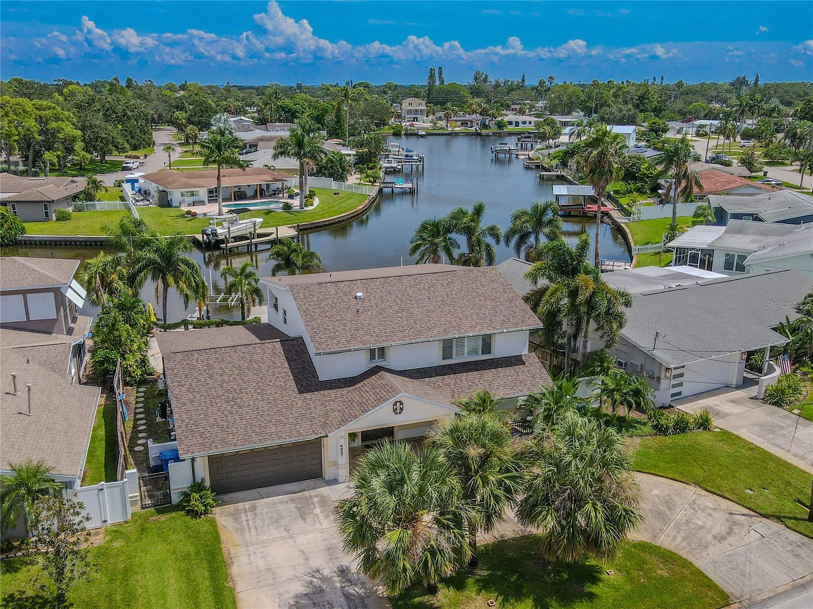 This upgraded two-story, 3-bedroom, 3-bath home with a pool and waterfront location blends Contemporary design with coastal Florida charm. With 71 feet of waterfrontage, a private dock, and direct canal access to the bay, this home is designed for seamless indoor-outdoor living. There’s a wide circular drive, and a two-car garage with a hurricane-rated door and battery backup. New A/C units and New Roof 2025. A 250 sq. ft. covered entry, featuring travertine tile, sets the stage for custom double doors crafted by A-1 Custom Glass, detailed with fleur-de-lis accents. Inside, the foyer showcases hardwood stairs with wrought-iron balusters, a polished wood handrail, and a Waterford crystal light. The open living and dining areas are finished with neutral tile, soft wall tones, crown molding, and custom plantation shutters. Expansive sliding glass doors and picture windows (triple-paned/hurricane-rated) frame views of the pool and canal, filling the home with natural light.
The updated kitchen features Mont Krest quartzite countertops, subway tile backsplash, and custom cabinetry. Features include a farmhouse sink beneath a picture window, butcher-block island, Restoration Hardware pendant lighting, GE under-cabinet dimmable lighting, and stainless steel appliances, including an LG InstaView refrigerator. A built-in wine/coffee bar with glass-front display cabinetry completes the space. The Florida/Sun room features walls of windows overlooking the water, while French doors lead to a 330 sq. ft. covered patio with travertine tile, dual ceiling fans, and built-in lighting. A pergola swing, a terraced lawn with a rope/fig vine border, and an upgraded travertine pool deck extend the outdoor living experience. The PebbleTec pool, featuring a 2024 pump/filter, Jandy/Zodiac salt generator, and 18,000-gallon capacity, is the backyard centerpiece. The private dock includes a 10,000 lb. boat lift, real TREX decking, and electric/water service. Upstairs, Brazilian Teak solid wood flooring extends throughout the hall, bedrooms, and closets. The spacious primary bedroom features dual built-in closets, abundant natural light, and sliding doors that open to a 330 sq. ft. covered balcony with panoramic views of the canal. The primary bath has a travertine floor and shower, Pearl jetted Jacuzzi tub, Cambria quartz countertops, and custom deluxe cabinetry with louvered doors, along with dual sinks and Delta designer hardware. The second bedroom includes plantation shutters, a walk-in closet, and an ensuite bath with marble flooring, a Cambria quartz vanity, a glass-enclosed shower, and deluxe cabinetry. The third bedroom has Brazilian Teak flooring, a ceiling fan, and louvered closet doors. A 1st floor third/pool bath features indoor/outdoor access, walk-in shower, custom vanity, vessel sink, and Delta fixtures. Additional highlights include triple-paned hurricane-rated windows and doors, lush tropical landscaping, and a spiral staircase connecting the balcony to the pool deck. This home combines refined interiors, extensive upgrades, and resort-style outdoor living in a prime waterfront setting. Located in Shore Acres, a waterfront community in northeast St. Petersburg with canal access, parks, and Tampa Bay views—just minutes from downtown’s restaurants, shops, and museums.
