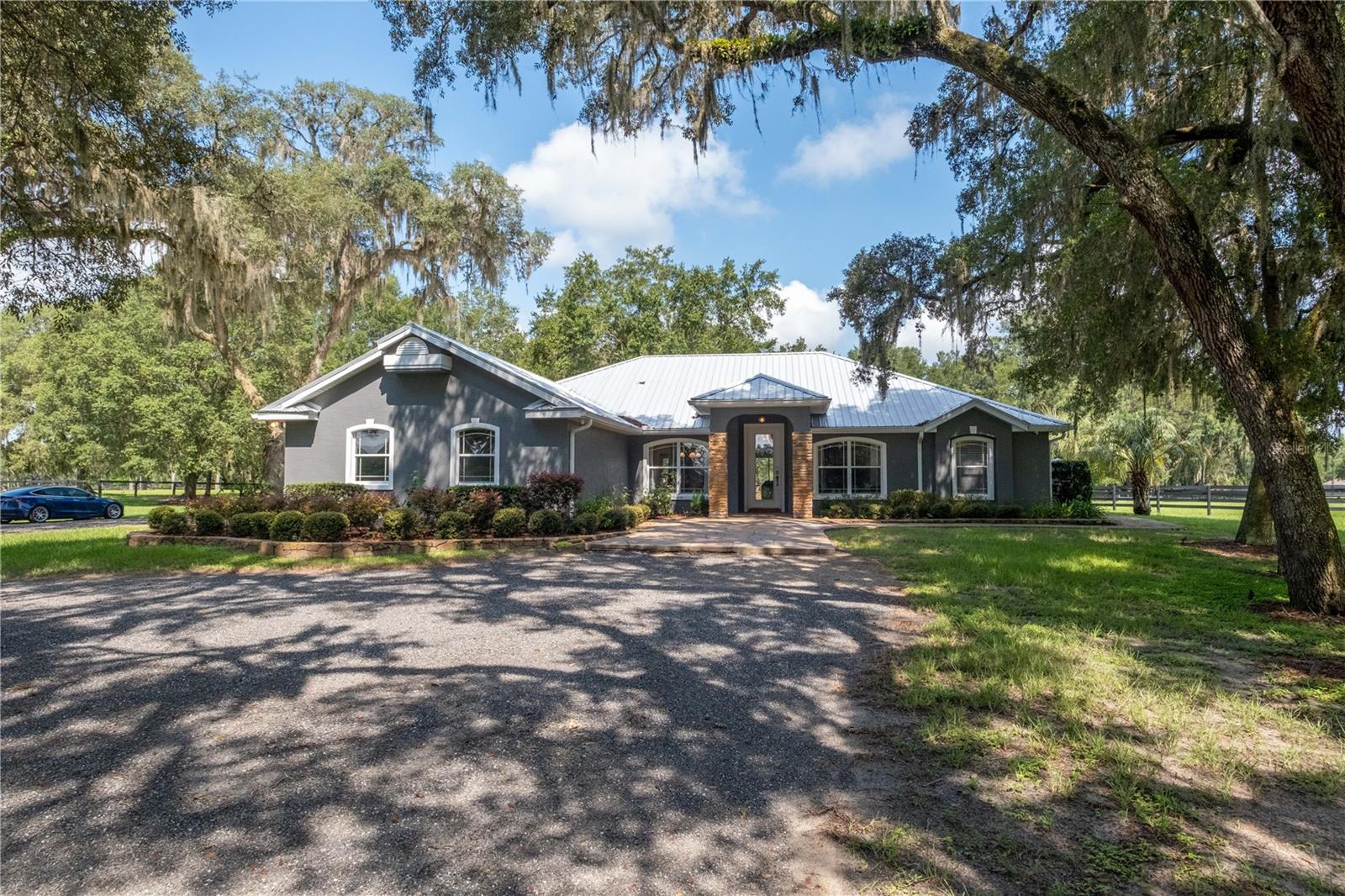 Gorgeous turn key Hunter Jumper estate in the heart of NW Ocala. Approx 4 miles to HITS and 4 miles to WEC. This 10 acre farm has everything you need for your hobby, amateur, or professional operation, whether you are seasonal or year round. The recently remodeled 3 bedroom 2 bath home features its own separate gated entrance to keep it private from all the horse traffic around the barn. Home has a very open floorplan with stained concrete floors throughout. Home features a circular driveway with additional parking, a large outdoor kitchen & outdoor fireplace, all stainless appliances, large office, huge primary suite, 2 car garage, and a diesel generator. Between the home and the 14 stall barn are 9 paddocks with 4 board fence, a 200'x200' irrigated GGT arena with french drains and crushed concrete base, a large grass riding area including a bank complex with stone wall, and a pond accented by 2 fountains and firepit with stone bridge. The spacious center aisle barn has its owned gated entrance, 14 stalls, 2 washracks, grooming area, new office/apartment, new laundry room, full bath, and has 4 RV plugs. There is a trailer parking area. All of the paddocks have 12'-16' lanes in between them and the property line. Must see!