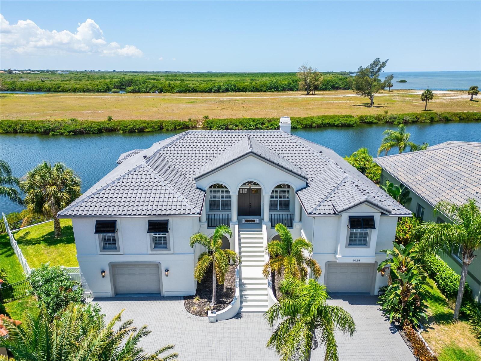 Check out your views from this coastal luxury waterfront POOL home with 140 feet of water shoreline! This exquisite property features 4 bedrooms and 3 full and one half bathrooms with wraparound water views including stunning views of Tampa Bay and the St. Petersburg skyline. Prepare to be captivated by the breathtaking sunset views. As you enter this coastal paradise, you're greeted by panoramic water views, 13 foot ceilings, travertine flooring throughout, an inviting great room with gas fireplace and dining area open to the kitchen with an additional seating area. This home is an entertainer's dream. Sliders from living area lead out to your heated salt water pool and covered lanai area. This makes for a perfect set up for all your gatherings. When its time to unwind head to the primary bedroom with ensuite and 2 walk-in closets, plus sliders that lead out to the lanai area. The primary bath includes double sink vanity, separate soaking tub and walk-in shower. Opposite side of the home you will find a guest bedroom with ensuite, plus 2 additional bedrooms and full hallway bathroom. The attractive staircase leads to laundry room with sink and work area. From here you will enter into your garage with 5 panel doors for boat and lifted truck clearance. Garage space includes 2,900 sq. ft., workshop area and half bath. This space can hold up to 6 cars. This kind of storage is hard to find! Outside is where you will be spending most of your time. Enjoy your own private dolphin and manatee show from your covered boat dock with water, electric, fishing station, and 12,000 pound boat lift that can house a 35 foot boat. Plenty of dock space to sit and relax and watch the show! Leaving from your dock you are minutes away from the open waters of Tampa Bay. This is truly a boater's paradise! Feel safe and secure with home security system and 24 hour gated community of Symphony Isles. Home and dock tile roof installed 2023. This home also includes well water for affordable lawn irrigation. The community of Symphony Isles features 24 hour guard security at gate, community clubhouse for all social gatherings, community pool, playground, boat ramp and private beach for residents. Get to know your neighbors and make lasting memories at the vibrant community events throughout the year-from lively casino and Miami Vice nights to end-of-school-year party, and the dazzling Christmas lights that transform the entire neigborhood into a holiday wonderland all this and NO CDD!! Travel time to Tampa International Airport is 25 miles (35 minutes) MacDill Air Force Base is 27 miles (40 minutes) 1 hour to the beautiful beaches of Tampa Bay. This is the one!! Property taxes reflect no homestead.