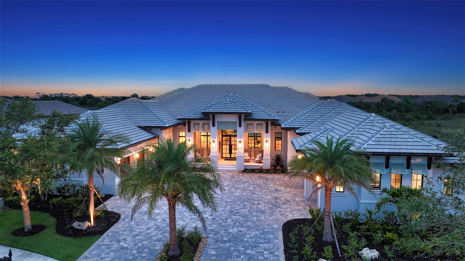 Tucked within the private, gated cul-de-sac enclave of Anchorage Place in The Lake Club, this six-month-old Stock Custom Home is a true architectural masterpiece. Set on two-thirds of an acre with sweeping views of lush natural surroundings, this 5,997 sq. ft., four- bedroom, five-and-a-half bath estate blends modern sophistication with serene, Florida resort-style living. Professionally decorated and fully furnished with new furnishings ($350K furniture package and $100K in recent upgrades), this stunning home embodies “organic modern” elegance—defined by earthy hues, layered textures, and refined finishes. The thoughtful design is evident from the moment you arrive, beginning with a smart glass iron front door with switchable privacy feature, intricate inlay flooring, and 15-foot tongue-and-groove rift-cut white oak ceilings that match the wood flooring throughout. The light-filled great room is anchored by a curved stucco wall with a 72” three-sided gas fireplace and features 10-foot pocketing sliding glass doors topped with transom windows, seamlessly connecting the indoors to the outdoors. A concealed TV, tucked behind remote-controlled artwork, adds to the room’s sleek, sophisticated design. Across the room, a custom curved kitchen hood echoes the architectural elegance of the fireplace wall. The chef’s kitchen is a showstopper with leathered quartzite countertops and backsplashes, dual islands with hidden storage, a large butler pantry, and luxury-grade appliances—including paneled Sub-Zero refrigeration and two Cove dishwashers, and a Wolf dual gas range with six burners, griddle, and double ovens, and a Wolf steamer oven and speed oven. Just off the kitchen is a stylish wet bar with ceiling-mounted shelving, decorative wall tiling, Sub-Zero wine refrigeration, and built-in ice machine—perfect for effortless entertaining. The open-concept dining area features corner pocket sliding doors for full integration with the lanai and pool area, while a generous and versatile bonus room offers flexible living space. The primary suite is a luxurious private retreat, complete with a cozy sitting area, a separate office with floor-to-ceiling built-ins, a morning bar, two custom walk-in closets, and a spa-inspired bath with integrated travertine wall, countertops and flooring, dual water closets, a walk-through shower, and an oval soaking tub. Each of the three guest suites includes its own full en-suite bath and walk-in closet, offering privacy and comfort for family or guests. Step outside to your own private resort—an expansive screened lanai (3,270 sq ft) featuring covered and open-air seating and dining areas, a full outdoor kitchen with island and bar seating, a 72” TV over a 48” linear vent-free fireplace, a saltwater pool and spa with a swim-up bar, and dramatic fire bowls—all set against the tranquil backdrop of preserved natural beauty. Additional highlights include a spacious laundry room with custom cabinetry, a symmetrical four-car garage, a whole-house gas generator, Lutron and Hunter Douglas shades, and an integrated “Smart Home” which includes house-wide boosted Wi-Fi with system integration for selected lighting and shades, all TVs, music, thermostats, all exterior lighting including the lanai and home security cameras. The home includes Starlink to ensure uninterrupted internet access. Located in Lakewood Ranch, Lake Club amenities include a clubhouse, pools, fitness center, tennis and pickleball courts, scenic trail.