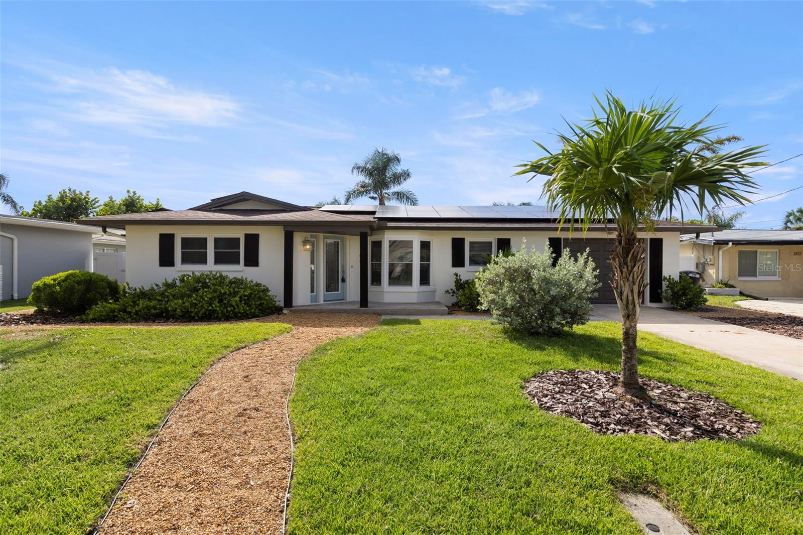 Welcome to your dream home in the heart of coastal Dunedin! This beautifully renovated 3 bedroom, 3 full bathroom residence offers modern upgrades and thoughtful details throughout, with the added benefit of fully PAID OFF solar panels. From the moment you step inside, you’ll be greeted by an open-concept floorplan with soaring vaulted ceilings, an abundance of natural light, and luxury vinyl plank flooring that flows seamlessly through the home. Freshly painted inside and out, every detail has been designed to feel warm and inviting. The kitchen is a true showpiece, featuring quartz countertops with a stunning waterfall edge island, stainless steel appliances, a sleek modern backsplash, and pendant lighting that ties it all together. The spacious owner’s suite boasts French doors leading to the backyard and a spa-inspired ensuite bathroom complete with a beautifully tiled walk-in shower. Both guest bathrooms have also been fully updated, offering style and functionality for family and guests alike. Step outside to your private oasis, where a screened-in lanai sets the stage for year-round entertaining. Enjoy the travertine pool deck, a newly pebble-teched saltwater heated pool with hot tub, and an outdoor kitchen with vent hood—perfect for gatherings big or small. Major updates include a new roof (2022), new AC (2022), and impact windows (2018), giving you peace of mind and efficiency for years to come. Beyond your front door, you’re just one block from the scenic Pinellas Trail and minutes from the Dunedin Causeway, Honeymoon Island State Park, and Caladesi Island beaches. Tee off at nearby Dunedin Golf Club or St. Andrews Links, cool off at Highlander Park & Pool, or spend the day exploring the vibrant shops, dining, and events of Downtown Dunedin. Don’t miss this rare opportunity to own a truly turn-key home in one of Tampa Bay’s most charming and sought-after communities.