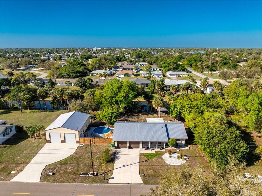 Freshwater waterfront home on two contiguous Port Charlotte lots offering water views, dock with benches, fruit trees (cherry, lime, avocado, mango) and a partially fenced yard. This 3-bedroom, 2-bath residence features ceramic tile floors throughout (laminate flooring in the enclosed lanai and large bonus room), an attached 2-car garage with a partitioned workout room, and metal roofs on both the home and detached garage building.  The power pole and power lines are being removed by the county shortly as all active services are now underground, according to the seller. 

Property includes a 30' x 40' x 12' steel detached garage with two 10' x 10' tall doors plus an 8' x 8' rear overhead door, an above-ground heated 18' fiberglass pool, screened gazebo with heated spa, fire pit and dock access—ideal for entertaining and outdoor living. Quick possession possible; see agent remarks for showings.
