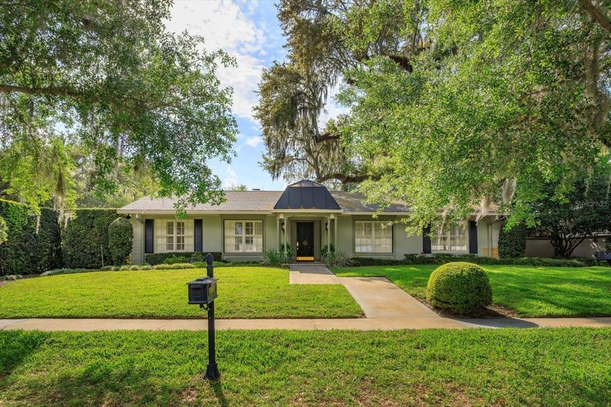 Tucked into the heart of highly sought-after Conway, this one-of-a-kind property offers something truly rare - an immersive garden retreat that feels worlds away while still being just minutes from everything Orlando has to offer.  Set on a .30-acre corner lot, the grounds are the true showpiece. Inspired by the charm and tranquility of a botanical garden, this lush, thoughtfully curated landscape features winding brick pathways, multiple private seating areas, and a stunning mix of mature plantings anchored by a centuries-old oak tree. The entire garden is enclosed by an impressive 8-foot architectural wall with decorative pillars and wrought iron gates adorned with artistic details, creating a sense of privacy and enchantment at every turn.  At the rear of the property, a 360-square-foot greenhouse with electric and irrigation is paired with an attached gazebo overlooking the gardens - an ideal space for relaxing, entertaining, or simply taking in the view. The outdoor living continues with a sprawling 570-square-foot brick patio and an additional side patio just off the kitchen, perfectly suited for morning coffee or intimate outdoor dining. A dedicated well services the garden, making it as practical as it is beautiful.  Inside, the home offers 2 bedrooms and 1.5 baths, filled with warmth and character. The primary suite features French doors that open directly to the garden, a spacious 10x12 closet/dressing room with built-in cabinetry, and a charming window seat. The Jack-and-Jill style bathroom includes a unique walk-through glass shower connecting two separate vanity and toilet areas.  The family room is both cozy and inviting, with custom built-in shelving, a striking whitewashed brick fireplace, and French doors leading to the outdoor living space. Crown molding runs throughout the home, and the original parquet wood flooring - beautifully maintained - adds timeless appeal to nearly every room.  The kitchen is equally charming, featuring whitewashed cabinetry, detailed woodwork, crown molding, white stone tile, and a bright eat-in dining area. The 2-car garage is outfitted with extensive built-in cabinetry, offering exceptional storage.  This is more than a home - it’s a private oasis designed for those who appreciate beauty, character, and a connection to nature, all in one of Orlando’s most desirable locations.