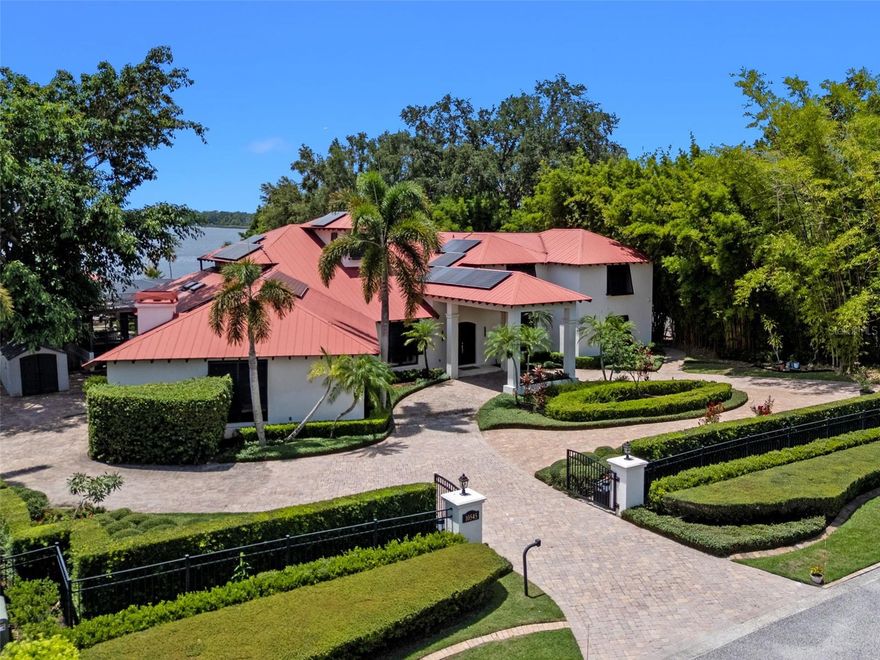 Enjoy stunning sunsets from your private estate with expansive views, located on Lake Down, the prestigious Butler Chain of Lakes in Windermere. This well-appointed property features 2.78 acres with fully fenced terraced grounds, electric security gates, brick pavers, mature landscaping for privacy, and 130 feet of water frontage with a seawall, enclosed boat house, dock, and lift.  The heated 7,363 square feet of living space includes the main home with 4 bedrooms and 5 bathrooms, as well as a lake guest house. Most rooms are graced with breathtaking views. Almost 10,000 square feet under roof, with a porte cochere,  extensive balconies, walkways, outdoor kitchen, and multiple patios. The screened pool area has an inviting resort feel, complete with a waterfall, slide, and hot tub, all connected to the outdoor entertainment areas.  Many quality upgrades, expansive ceilings with craftsman woodwork, wood and marble floors, formal dining with a music room, and fireplaces in the living, family room, and primary bedroom. The living room features a floor-to-ceiling window with remote-control blind, taking full advantage of the priceless view.   The main staircase gives a dramatic vantage point to appreciate the open floor plan, ideal for entertaining. The well-appointed kitchen features a  chef's prep kitchen, electric and Wolf gas double oven, two Sub-Zeros, double dishwashers, and a built-in espresso machine. All kitchen elements are set within rich wood custom cabinetry and granite countertops, with a breakfast room that leads to the pool area.  The guest bathroom, laundry & family room are all conveniently located near the pool. The primary suite is downstairs and includes a private screened porch, remote-control blackout blind, custom cabinet with washer & dryer, and a large master bath with a soaking tub, walk-in shower all with elegant stonework. The suite is adjoined by a generous custom closet, safe for valuables, private gym with mirror, rubber floor, bonus storage, and a private staircase to the upstairs. Upstairs features large bedrooms with lots of closet space, balconies overlooking the water with Ipe decks and a secondary  family room or playroom for the family. The lake cottage spells fun with balconies all around and views of the water and pool on three sides. Open beam ceilings, bamboo and new luxury vinyl wood floors, full kitchen &  living room upstairs with a full bedroom and bath downstairs complete with a wet bar.  The property has rear yard access down to the lake, great for boat parking or extra parking when you rally the team for a volleyball match on the court.   You can also utilize the tennis courts & private boat ramp just a short walk down the street. There are too many low maintenance, cost saving features to list, but a few include; energy efficient solar power, metal roof, and three on demand propane powered gas water heaters.  There are over $55,000 in solar panels that will save countless dollars over the years and is good for the environment.  The electric bills are minimal.   As I mentioned earlier Ipe hardwood is the best exotic hardwood the industry has to offer and it was used on the extensive decks for low maintenance. A new two horse sprinkler pump was recently installed that draws from the lake to maintain the exotic landscape. The durable easy to clean composite dock has two lifts & two boat slips.   The owner will even throw in the $50,000 ski boat (approx Value) with an acceptable offer.