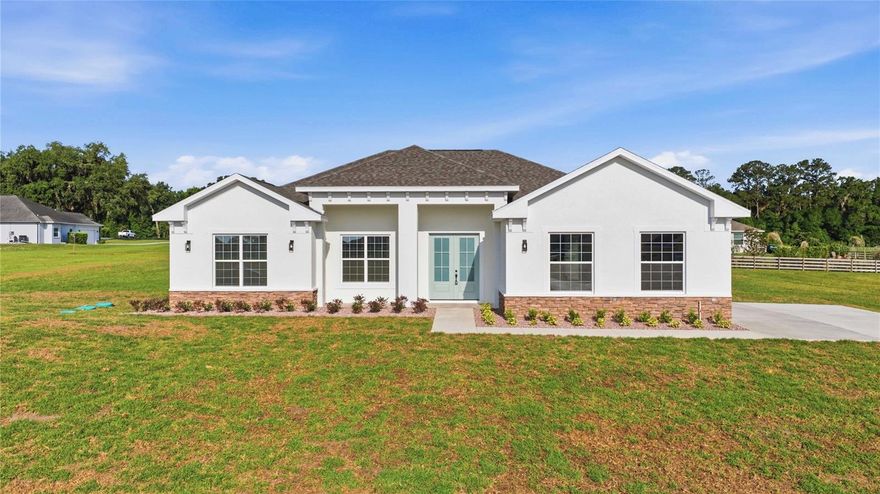Welcome to Irish Acres in Ocala, Florida—where custom design meets everyday comfort. This stunning 4-bedroom, 3-bath home also features a versatile flex room, spacious indoor laundry, and an oversized garage.
The kitchen truly steals the show, showcasing crisp, clean lines, under-cabinet lighting, soft-close cabinetry, a double oven, wine fridge, and an expansive island with additional seating—perfect for gathering and entertaining.
Designed with a triple-split floor plan and open-concept layout, this home is ideal for both privacy and hosting. Soaring 10-foot ceilings throughout and a dramatic 16-foot vaulted ceiling in the living room create a bright, airy feel, beautifully complemented by elegant crown molding. (Some photos have been digitally enhanced or staged)
No detail was overlooked—from the 10-inch ceramic wood-look tile flooring to the 7.25-inch baseboards throughout. Enjoy relaxing mornings and peaceful evenings on the covered front and back porches.
Located in a quiet, luxury gated community, this home offers both tranquility and convenience—just minutes from everything Ocala has to offer.