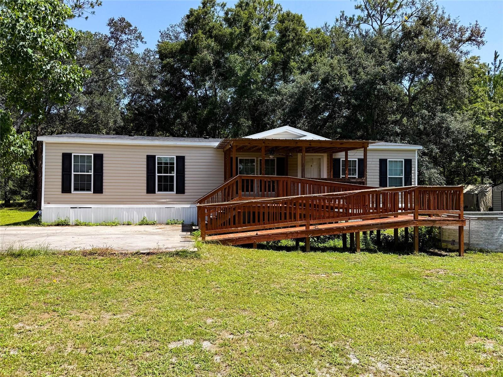 Short Sale. Welcome to this 4-bedroom, 2-bath 2021 mobile home nestled on approximately 1 acre in a peaceful neighborhood. Offering 1,664 sq ft of comfortable living space, this home features an open-concept layout with a spacious kitchen island that flows seamlessly into the living room—perfect for gathering and entertaining. The split floor plan offers privacy, while generous closets provide storage. Enjoy the convenience of a laundry room just off the kitchen and relax on the covered front porch, complete with an accessible ramp and several outbuildings. Surrounded by mature trees and quiet surroundings, this property offers the ideal blend of space, comfort, and tranquility. Easy commute to Gainesville and Jacksonville.