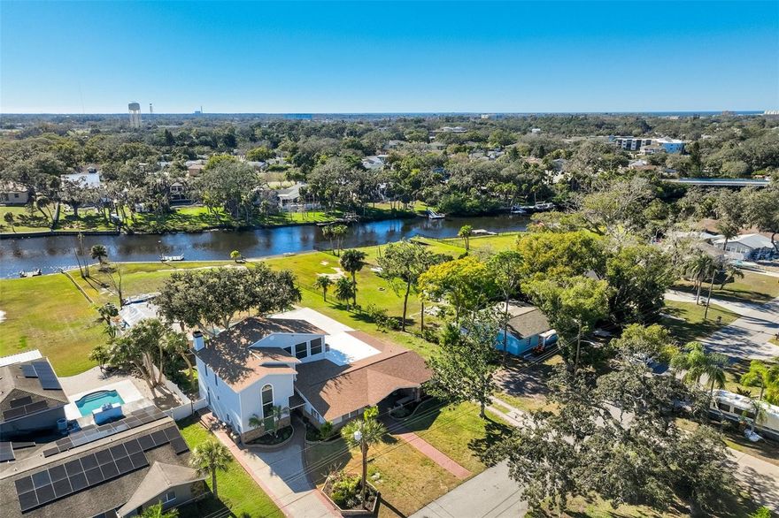 HOME HAS NEVER FLOODED ! 14' ELEVATION per Elevation Certificate ! A rare waterfront estate where luxury meets freedom—set on a nearly one-acre double lot with approximately 160 feet of frontage on the Cotee River, offering direct access to the Gulf of Mexico. Private, elevated, and beautifully reimagined, this is one of  Downtown New Port Richey’s most exceptional hidden gems in this Golf Cart Friendly Community!
Inside, over 4,000 sq ft of light-filled living unfolds with soaring ceilings, expansive Andersen windows, porcelain tile throughout, and a striking wood-burning fireplace anchoring the main living space. The home was thoughtfully updated to feel both grand and inviting—perfect for entertaining or effortless everyday living.
The showpiece kitchen, fully renovated in 2024, is designed to impress with all-new appliances, generous workspace, and seamless flow into dining and living areas. Whether hosting intimate dinners or lively gatherings, this home was built for connection.
The layout offers flexibility and privacy, with four bedrooms on the main level and a true upstairs primary retreat. The primary suite features a spa-inspired marble bath and opens to a screened deck with sweeping views of the river, pool, and expansive fenced grounds—your personal escape above it all.
Step outside to over 2,000 sq ft of covered and screened veranda, overlooking a newly refinished saltwater pool, lush landscaping, and tranquil waterfront. From sunset swims to dockside mornings, boating, fishing, or entertaining under the stars—this is Florida waterfront living at its finest. A private dock, RV pad with 50-amp hookup, workshop with electric, and wide rolling gate add both convenience and capability.
Major upgrades include Owens Corning shingle roof (2025), flat roof (2024), HVAC systems (2022), hot water heaters (2022), full interior paint, LED lighting, landscape lighting, updated baths, and more—all meticulously maintained. The home has never flooded and sits elevated above the river. No HOA.
Offered mostly furnished (excluding sentimental items) and in downtown New Port Richey, parks, beaches, and the upcoming Grand Blvd bridge & riverwalk, this is more than a home—it’s a lifestyle statement.