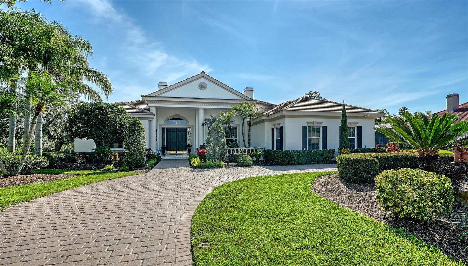 Tucked away on nearly 1.5 acres at the end of a quiet cul-de-sac, this beautifully updated River Club residence offers timeless style and classic Florida living with serene lake and preserve views. A new roof and freshly painted exterior enhance the home’s curb appeal, while a circular driveway welcomes you to a thoughtfully designed interior. The 3,662 sq ft split-bedroom layout includes three bedrooms, three full baths, and a dedicated home theater with platform seating, 11-foot screen, and impressive surround sound. Rich wood flooring, crown molding, built-in speakers throughout, and custom built-ins add character and comfort, while the kitchen features granite countertops, a prep island with wine fridge, walk-in pantry, and a spacious dinette framed by an aquarium window. Ideal for entertaining, the living room showcases a fireplace with built-in shelving and storage, full wet bar, and flows seamlessly into the dining room. Sliding glass doors from both the living and family rooms open to a showstopping tri-level screened lanai with pool and spa, all overlooking the tranquil natural backdrop. The primary suite is a private retreat with lanai access, plantation shutters, two walk-in closets, and a luxurious bath with soaking tub, walk-in shower, dual vanities, private water closet, and linen closet. Set within the established community of River Club, this exceptional home offers easy access to the world-renowned Gulf Coast beaches, the shopping, dining, and entertainment venues of Lakewood Ranch and Sarasota, top-tier medical facilities and A-rated schools.