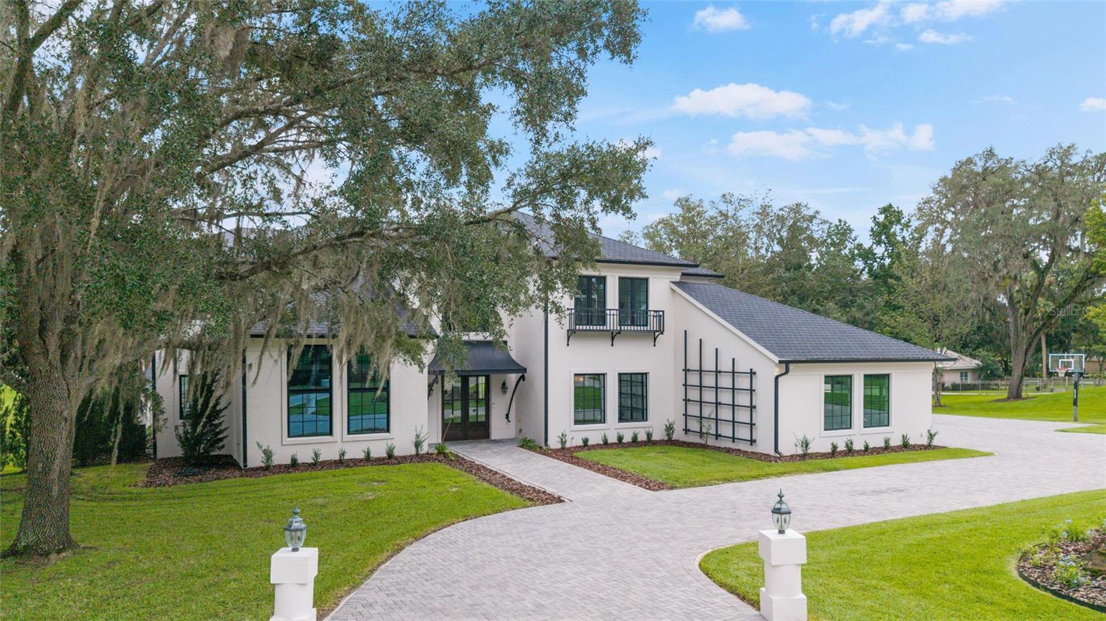 Nestled in the Country Club of Ocala, this beautifully renovated 5-bedroom, 4.5-bathroom home offers luxurious living, thoughtful design and sweeping views of the golf course—best enjoyed from the upstairs balcony off the expansive primary suite. With over 5,000 square feet of updated interior space and premium outdoor amenities, this home is truly one of a kind. Completely reimagined in a multi-year renovation, this home was taken down to the studs and rebuilt with high-end finishes and energy-efficient upgrades throughout, including all-new insulation, upgraded windows and mahogany exterior doors. Step into a grand 2-story foyer with soaring ceilings, a dramatic stone feature wall and a handcrafted wrought iron staircase that immediately sets the tone for this home. The family room is a showstopper with its floor-to-ceiling windows, brick feature wall, and inviting fireplace—flooding the home with natural light and warmth. The open-concept kitchen is a chef’s dream, featuring custom cabinetry, new quartz countertops, top-of-the-line appliances and a large center island—all framed by stylish shiplap walls that continue into the charming breakfast room. The adjacent formal dining room impresses with another brick accent wall. Opposite the formal dining room, a versatile flex room with custom built-ins, a wet bar, and beverage refrigerator is ideal for use as a game room, home office, or study. Two generously sized guest bedrooms with private en-suite baths, a powder room for guests, and a well-appointed laundry room with two sets of washers and dryers complete the first floor. Upstairs, a landing overlooks the living space below and leads to the primary suite, which features a sitting area and direct access to a private balcony overlooking the golf course. The spa-like primary bathroom includes a large tiled shower, round soaking tub, dual vanities and custom his-and-hers closets. Two additional upstairs bedrooms share a Jack-and-Jill bath with double vanities and a tub/shower combo. A large bonus room, already wired for a home theater, could also easily be converted into s a sixth bedroom, with space and plumbing available to add an additional bath. Enjoy Florida living at its finest in the thoughtfully designed outdoor space, which includes a covered patio, resurfaced pool (remarcited just a few years ago), new pool pump, built-in fire pit and an updated cabana with full bath and new split-unit A/C—all surrounded by aluminum fencing. Additional updates include: new air conditioning units (both in 2020), new roof (2018), premium LVP wood-look flooring throughout and fully remodeled bathrooms and kitchen. This exceptional property offers comfort, flexible living spaces, and unbeatable views—all within one of Ocala’s most desirable gated communities. Don’t miss the chance to own this extraordinary home in the heart of the Country Club of Ocala—where every detail has been thoughtfully curated.