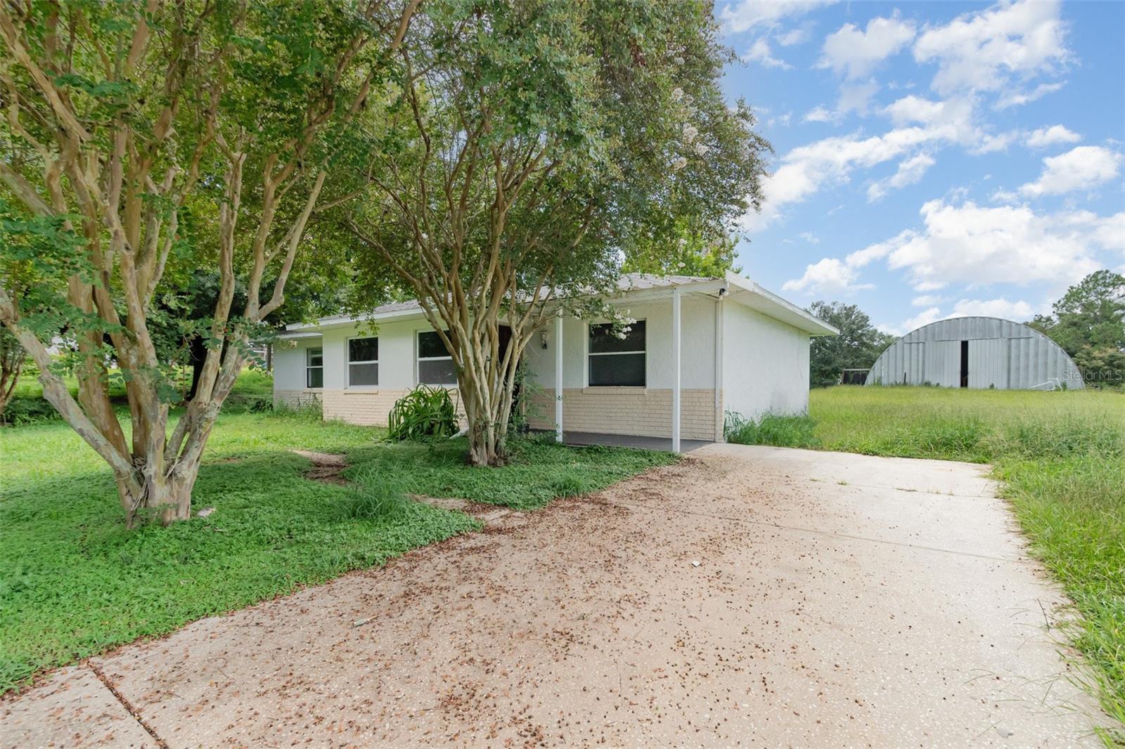 BELOW APPRAISED VALUE! Spacious 3-Bedroom Home on 2 Acres with Huge Workshop with No HOA! Welcome to your own private slice of Florida living! Situated on over 2 acres, this charming 3-bedroom, 2-bath home offers space, freedom, and endless possibilities just minutes from The Villages. Step inside to an open-concept layout that seamlessly blends the kitchen and living areas, perfect for entertaining or everyday living. The split-bedroom floor plan offers privacy, with a spacious primary suite featuring a large walk-in closet. The guest bath includes a convenient tub/shower combo. Out back, you’ll find a massive enclosed workshop ideal for hobbies, a home business, extra storage, or even your dream man cave or she-shed. Bring the tools, toys, or even a boat there’s plenty of room and NO HOA restrictions. Major updates include a new roof (2020) new AC (2015), new drain field (2020) giving you peace of mind. All of this, just a short drive to top-rated shopping, restaurants, hospitals, and entertainment in The Villages. Acreage, flexibility, and location this one has it all. Schedule your showing today!