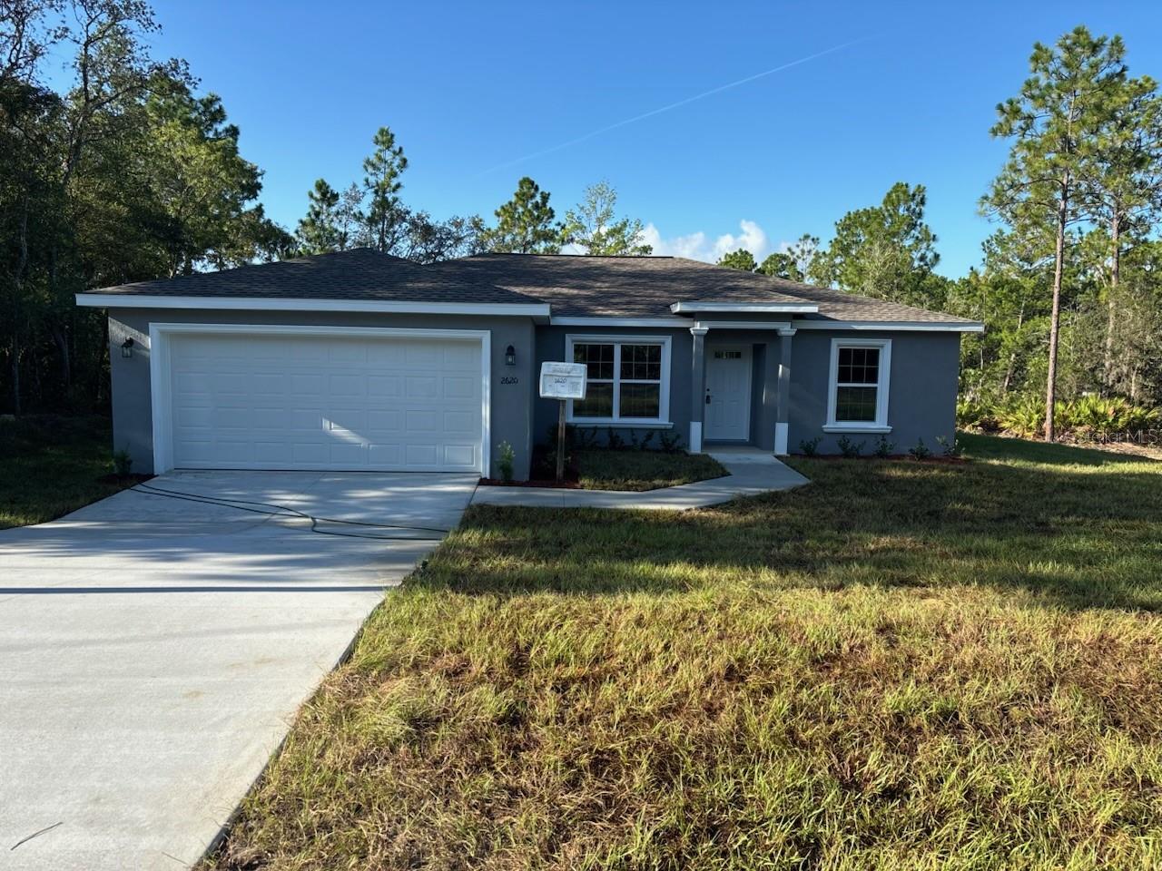 NEW CONSTRUCTION. MOVE-IN READY! This beautifully designed Key West model in Dunnellon offers 3 bedrooms, 2 bathrooms, and 1,405 square feet of comfortable living space. Sitting on a secluded lot at the end of a quiet street with woods behind, this home offers peace and privacy with very few nearby neighbors. Inside, you’ll find the builder’s largest master suite, featuring a spacious layout and a modern glass-enclosed shower with upgraded marble-look tile. The living room has a vaulted ceiling that adds to the open feel, and the kitchen is outfitted with stainless steel appliances, granite countertops, a subway tile backsplash, and custom white shaker cabinets with soft-close drawers. A kitchen pantry adds extra storage, and the luxury vinyl plank flooring runs throughout the entire home. The guest bathroom includes a tub and shower combo with matching upgraded tile. Enjoy energy-efficient double-pane windows, a 30-year architectural shingle roof, and concrete block construction built to last. The laundry room includes an upgraded cabinet package, and the attached 2-car garage comes with an opener and remotes. Relax outside on the covered patio, surrounded by natural beauty. Located in flood zone X, this home is high and dry and does not require flood insurance. Best of all, there are no HOA fees, giving you more freedom and flexibility.