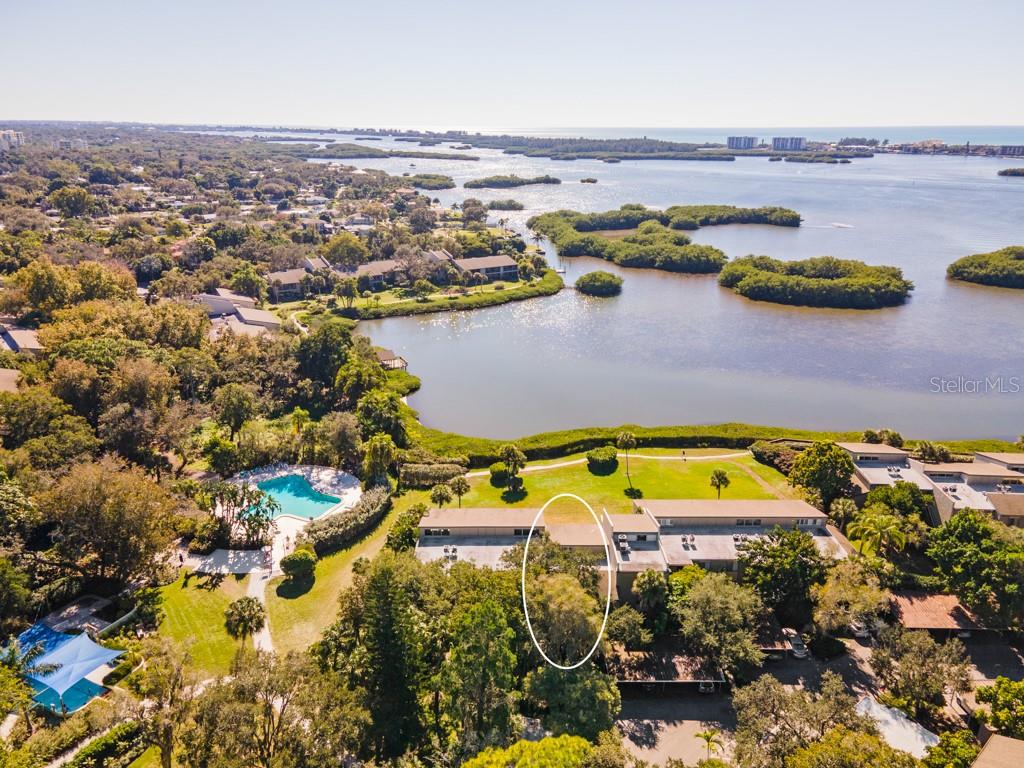 Welcome to your fully furnished, TURNKEY, Bayfront water view home! Simply move-in and take in the tranquil Little Sarasota Bay and marvel at the dolphins, manatees, birds, and other wildlife. Enjoy incredible sunsets and star gazing in the evenings from your enclosed lanai. This stunningly remodeled 3 bed/2 bath condo features soaring cathedral ceilings, clerestory windows, generous open floor plan with a high-capacity AC system, water heater, and luxury vinyl flooring throughout. This bright and peaceful second-floor unit is centrally located within the 75-acre, botanic garden-like setting of Pelican Cove. The historic Wilbanks clubhouse is only steps away, where the main heated resort-style pool awaits. Across the way is the private picturesque 87-boat slip harbor. Boat and kayak to Midnight Pass and have direct access to the gulf! Residents gain entry to the unique blend of natural habitats, miles of scenic trails, a fitness room, multiple heated pools and hot tub. There are six new pickleball courts and resurfaced tennis courts with active clubs for play. Many more recreational and cultural events are hosted year around. Robust live music, art and culture, and educational seminars are abundunt in season. The community is also conveniently located with shopping and restaurants near by. Siesta Key and downtown Sarasota are in very close proximity as well. You will love this phenomenal unit in this one-of-the-kind, gated, maintenance-free living community of Pelican Cove!